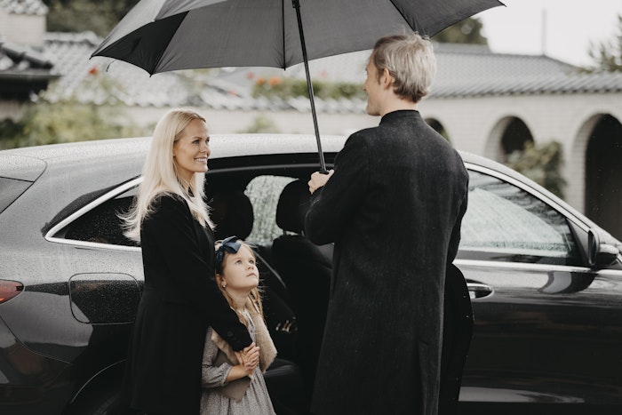Familie ved bil i regnvejr