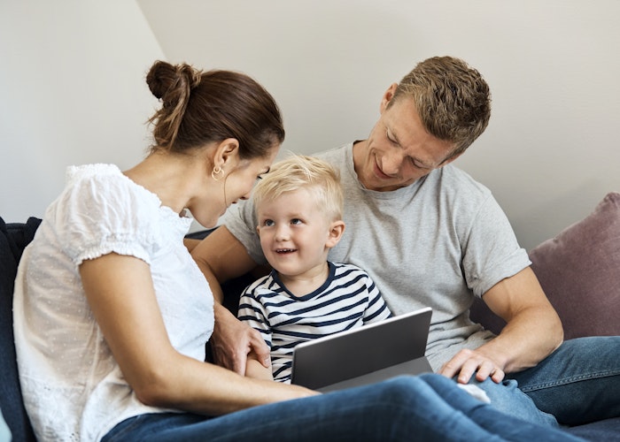 Forældre og barn med tablet i sofa