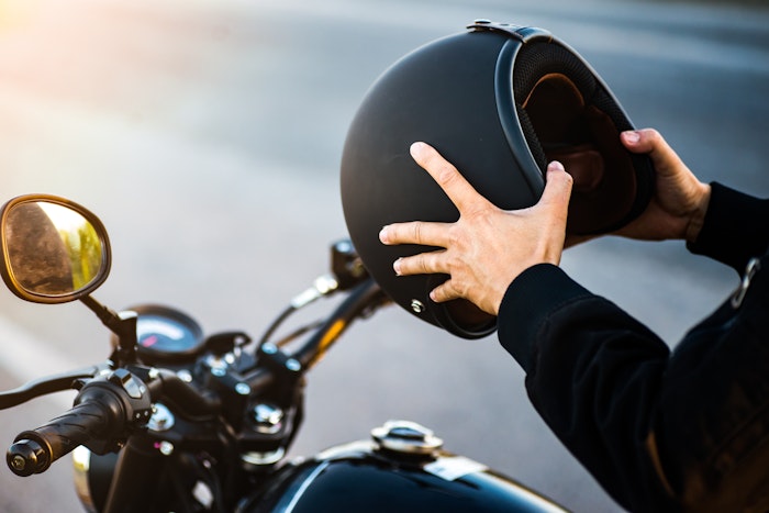 Mand på motorcykel med hjelm i hånden