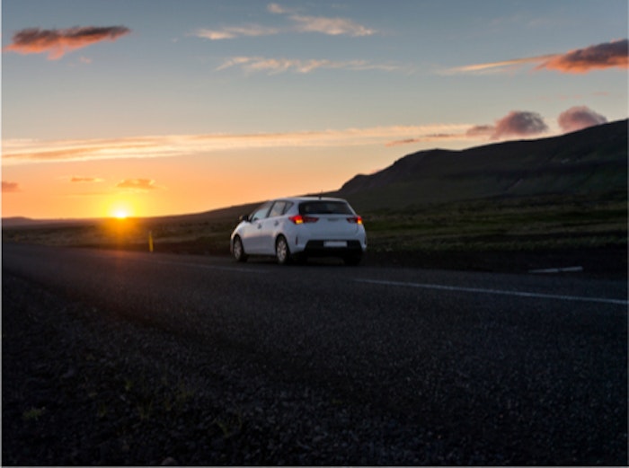 hvide bil kører på vej ved solnedgang