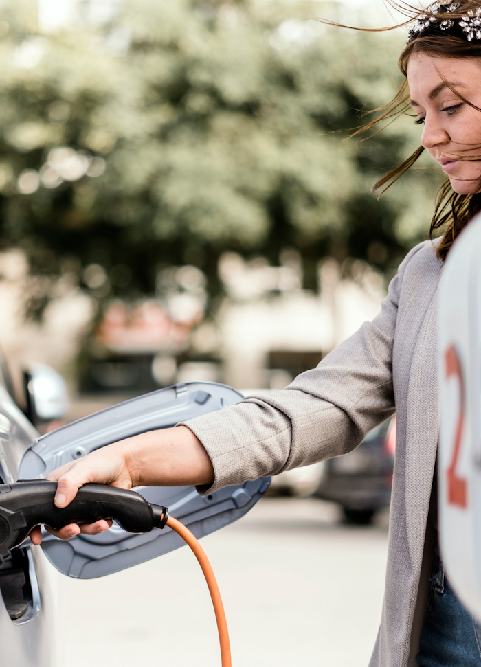 kvinde oplader bil i byen
