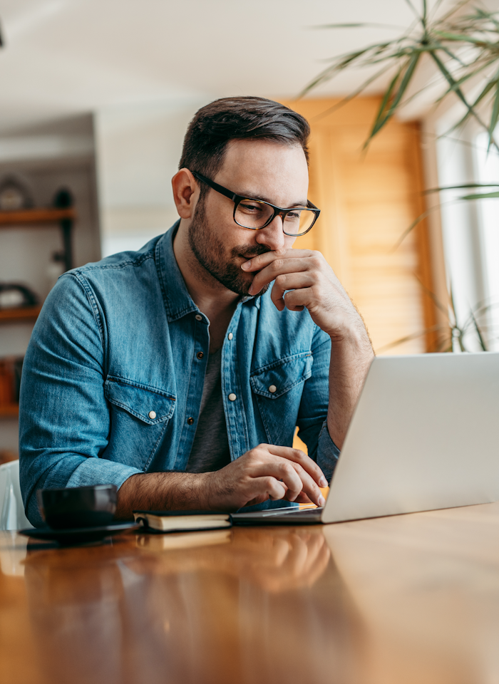 Mand sidder og tænker ved sin computer