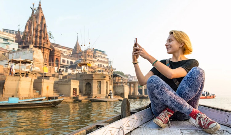 A woman on a boat on a river taking a photo