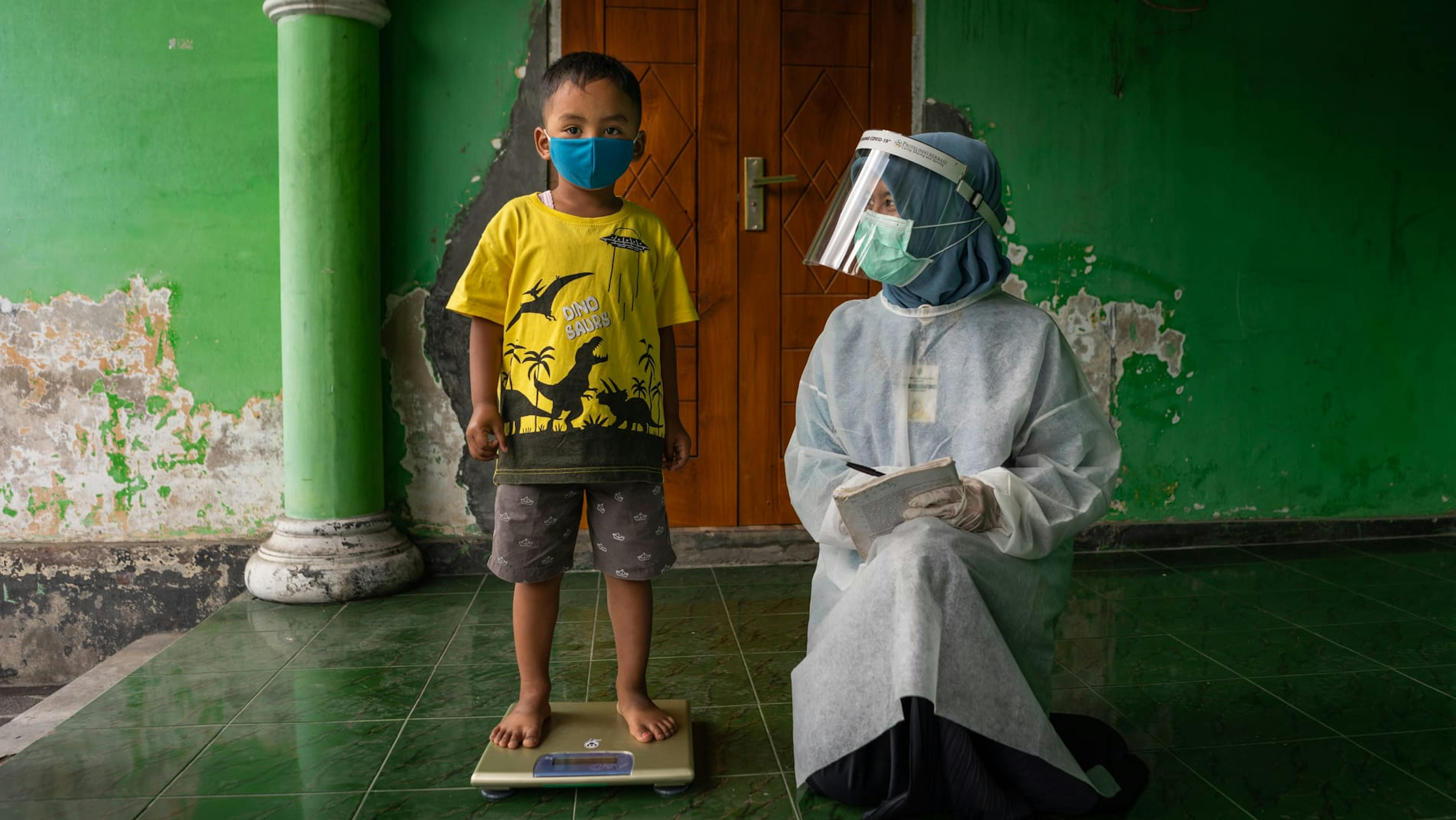 Un bambino viene pesato in una postazione sanitaria nel villaggio di Sidorejo, in Indonesia