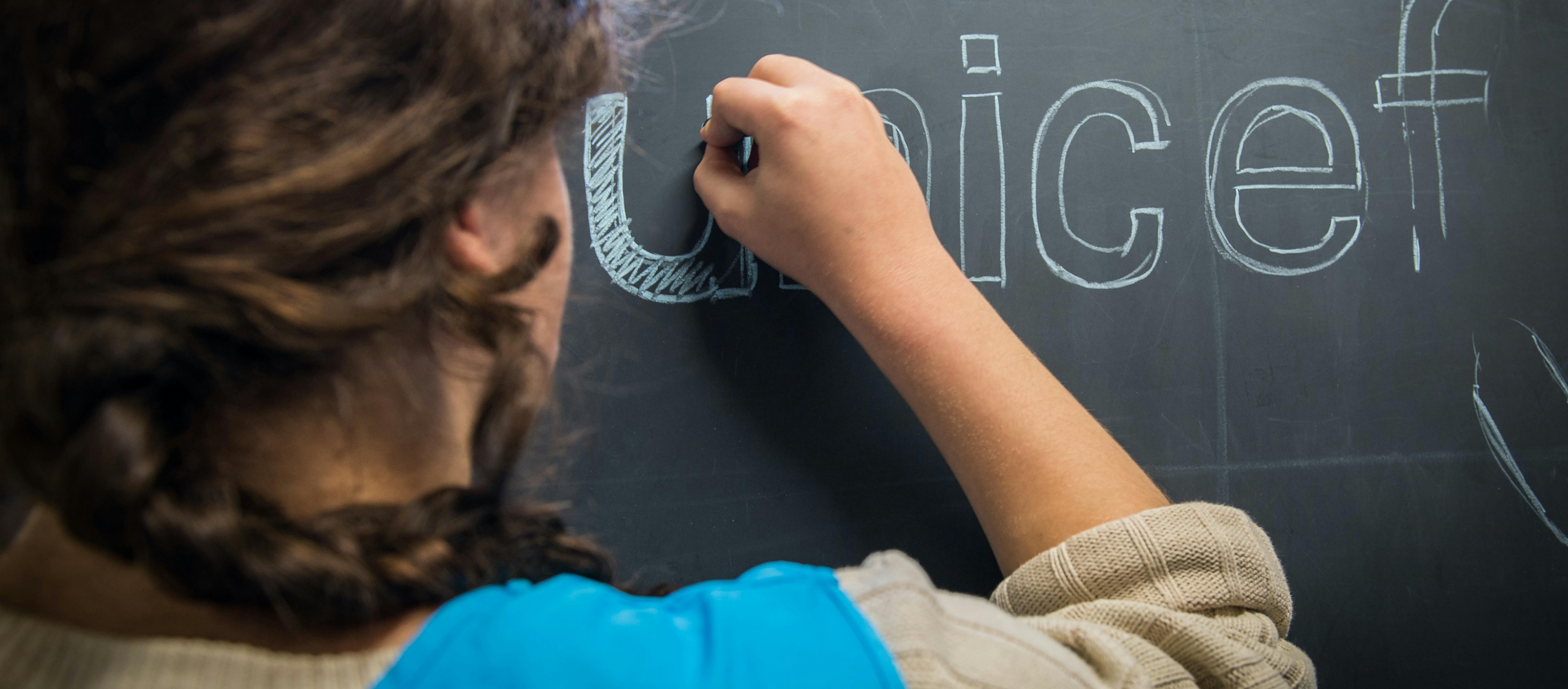 Volontaria disegna alla lavagna il logo UNICEF