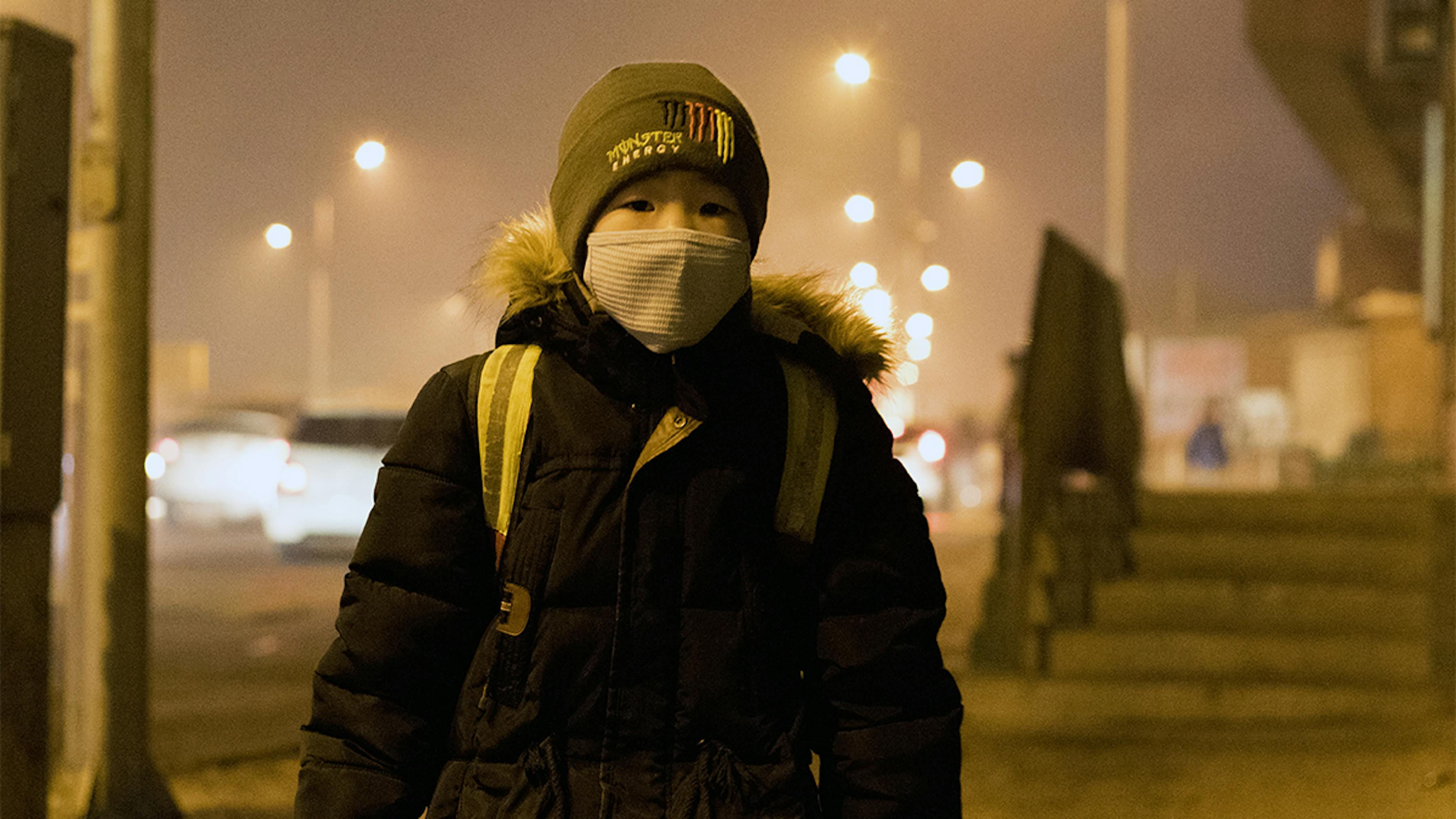 Mongolia, un ragazzo con una mascherina si protegge dall'inquinamento atmosferico molto elevato.