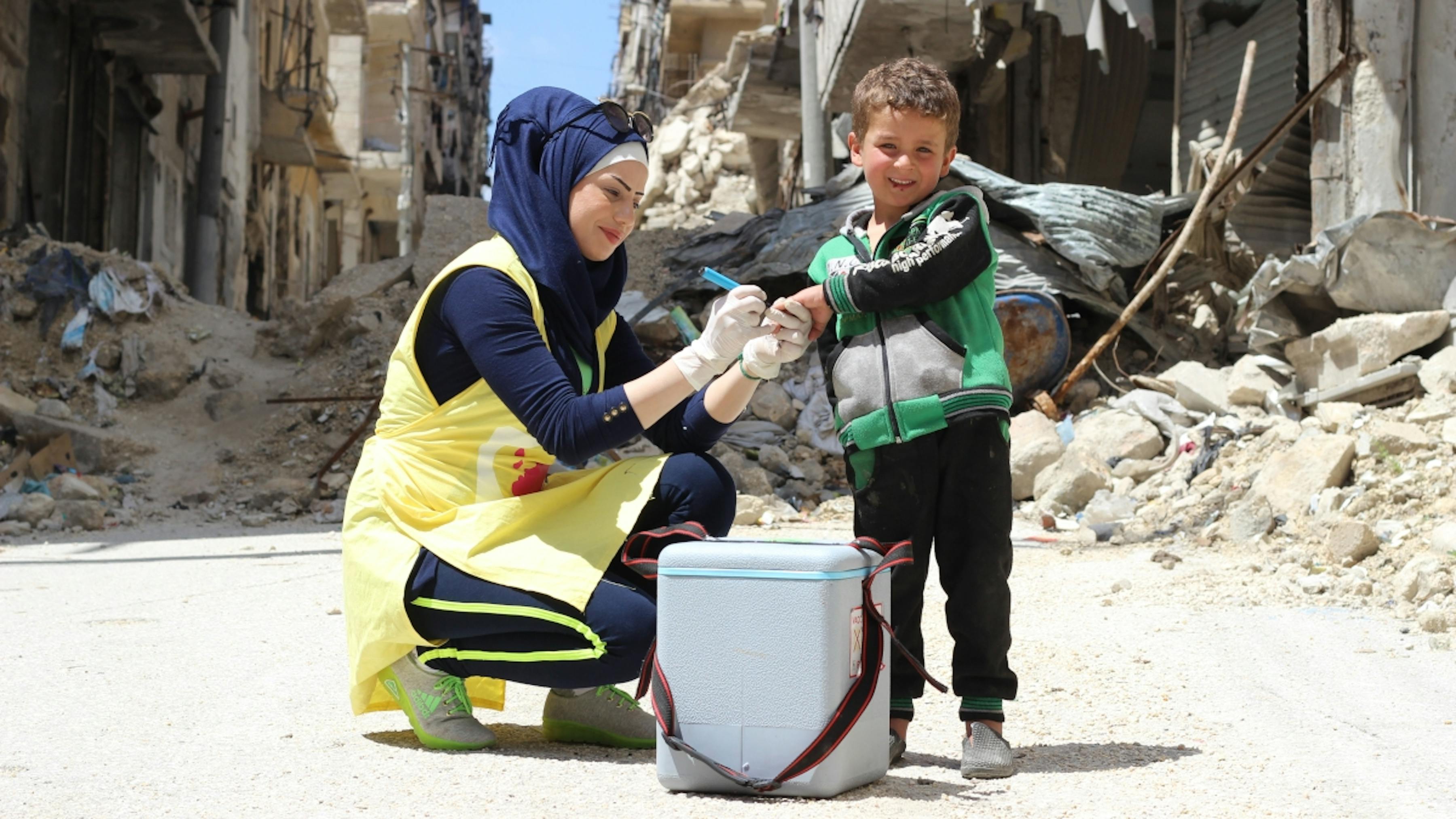 Siria, un operatrice sanitaria vaccina Yousef, di 5 anni nel quartiere di Hulluk ad Aleppo