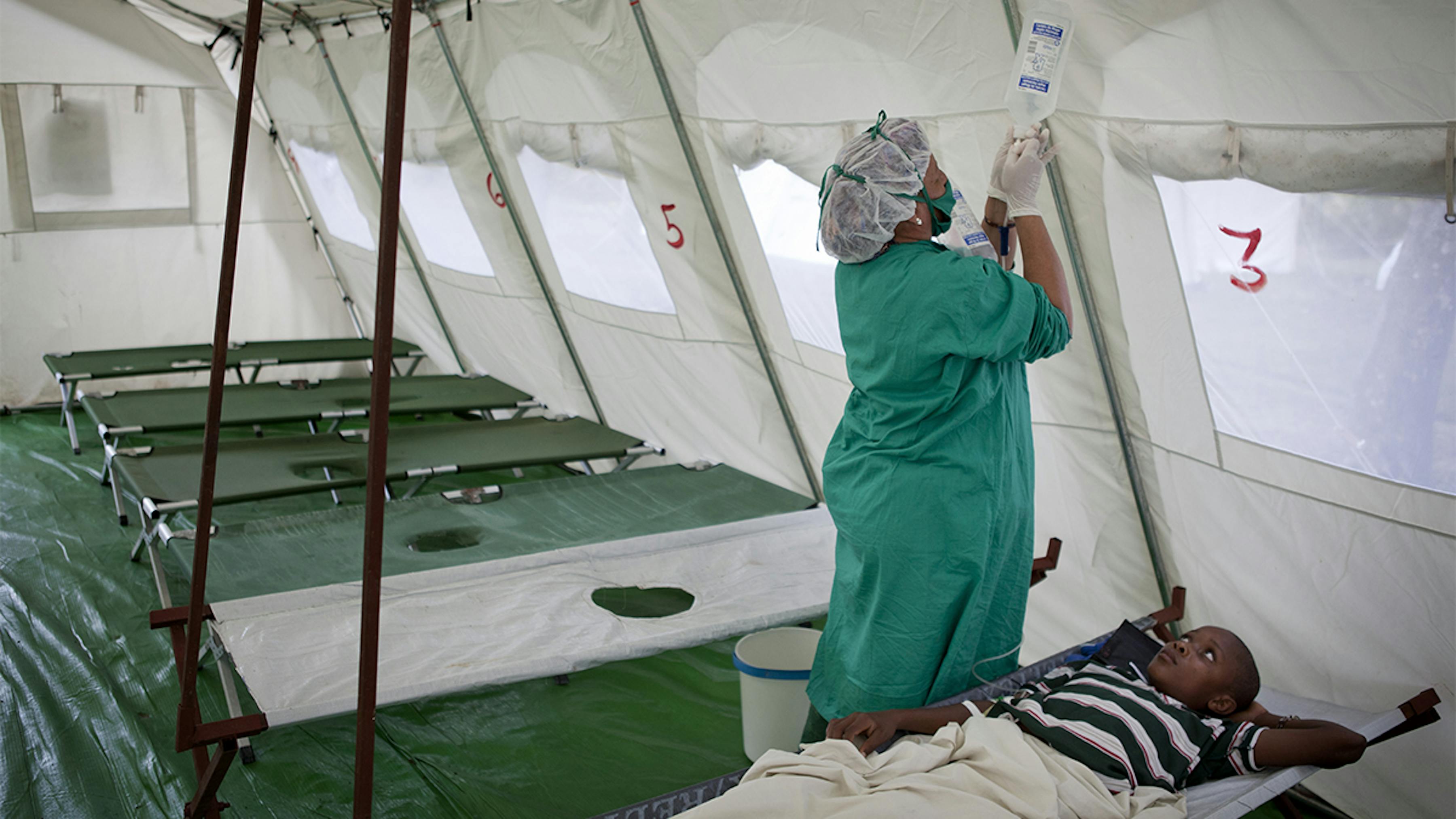 Haiti, una dottoressa sostituisce un sacchetto di liquidi per via endovenosa ad un ragazzo affetto da colera