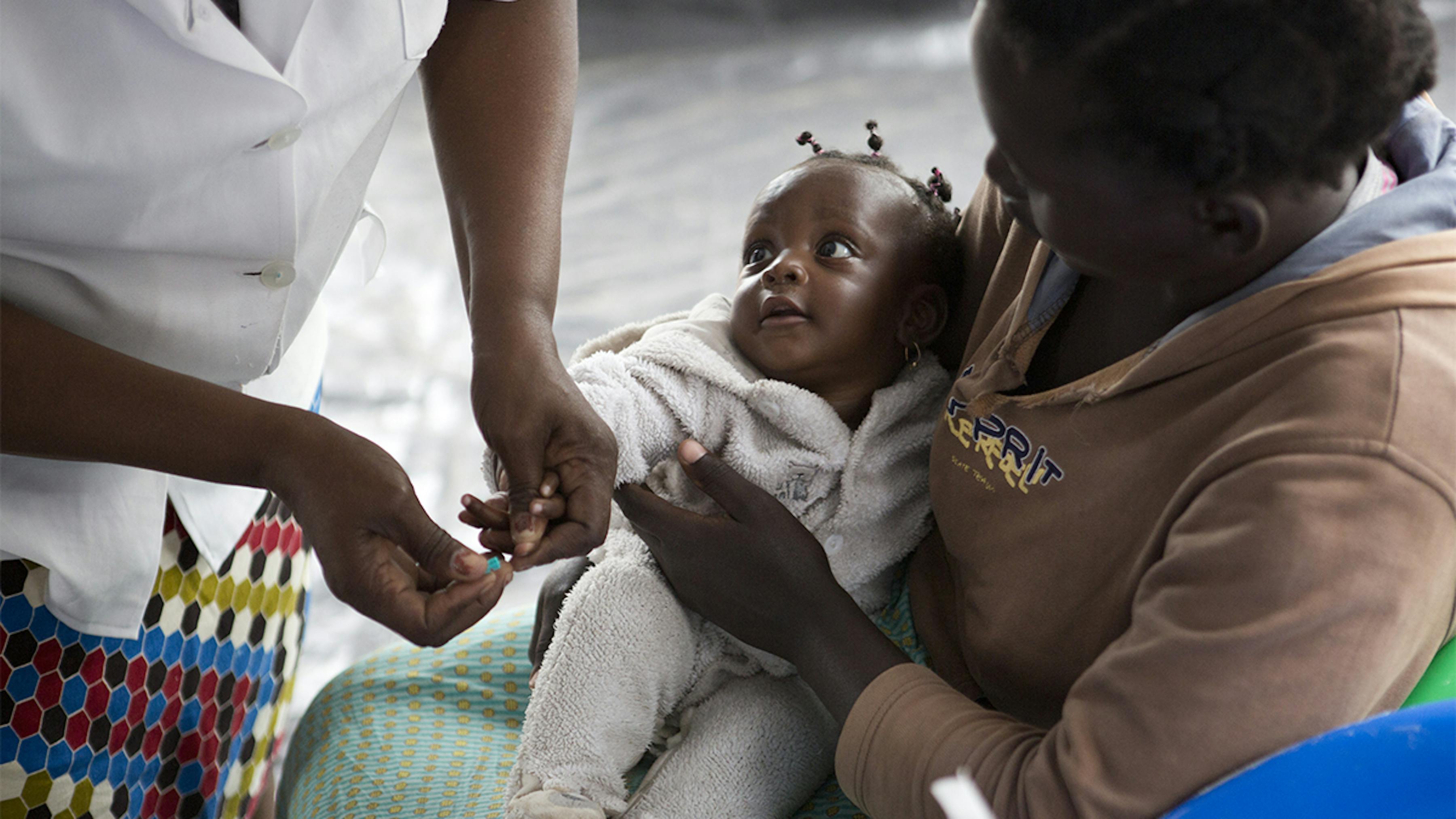Mozambico, a una bambina viene effettuato il test della malaria.