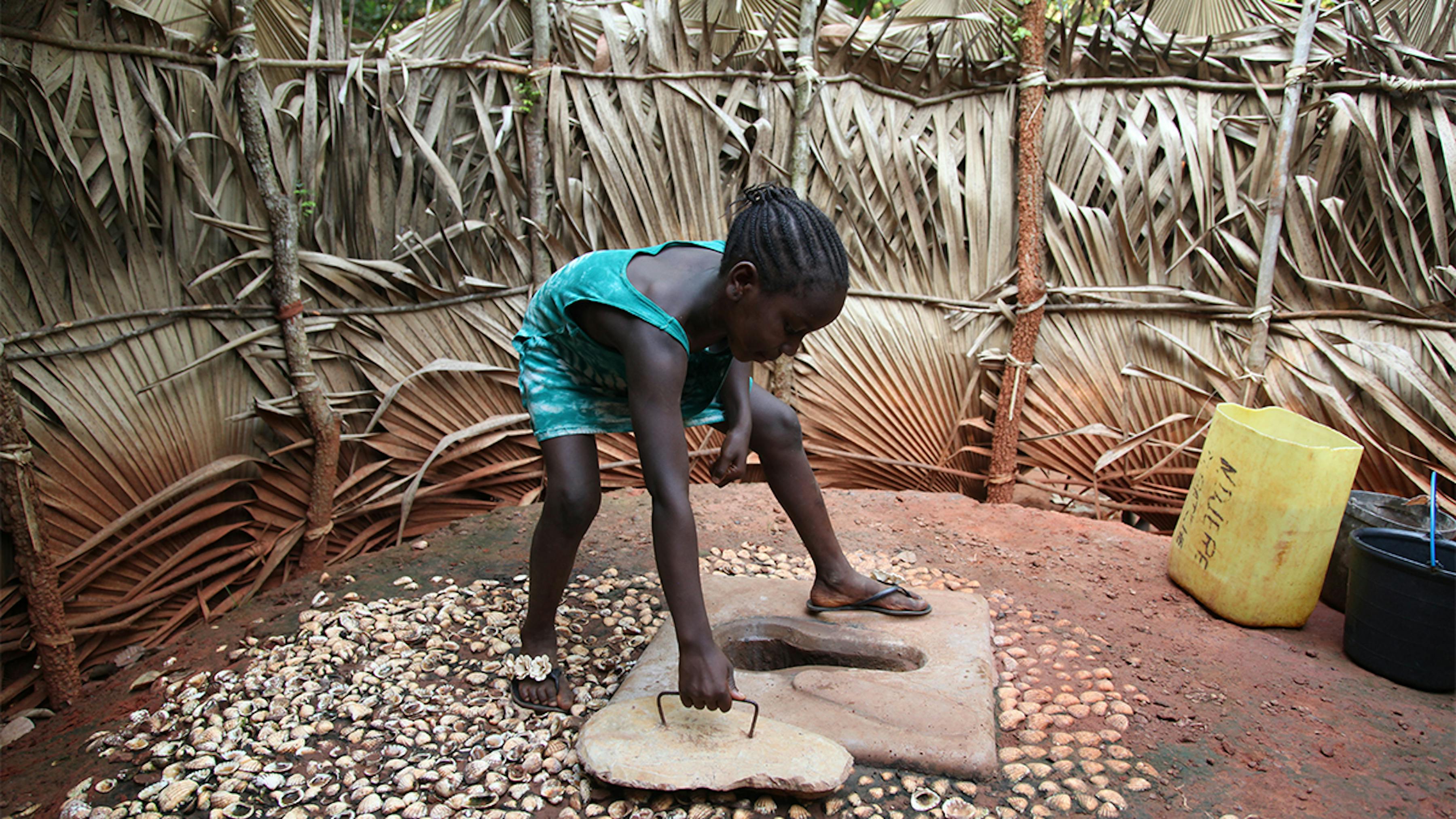 Guinea Bissau, una ragazza chiude una latrina a fossa