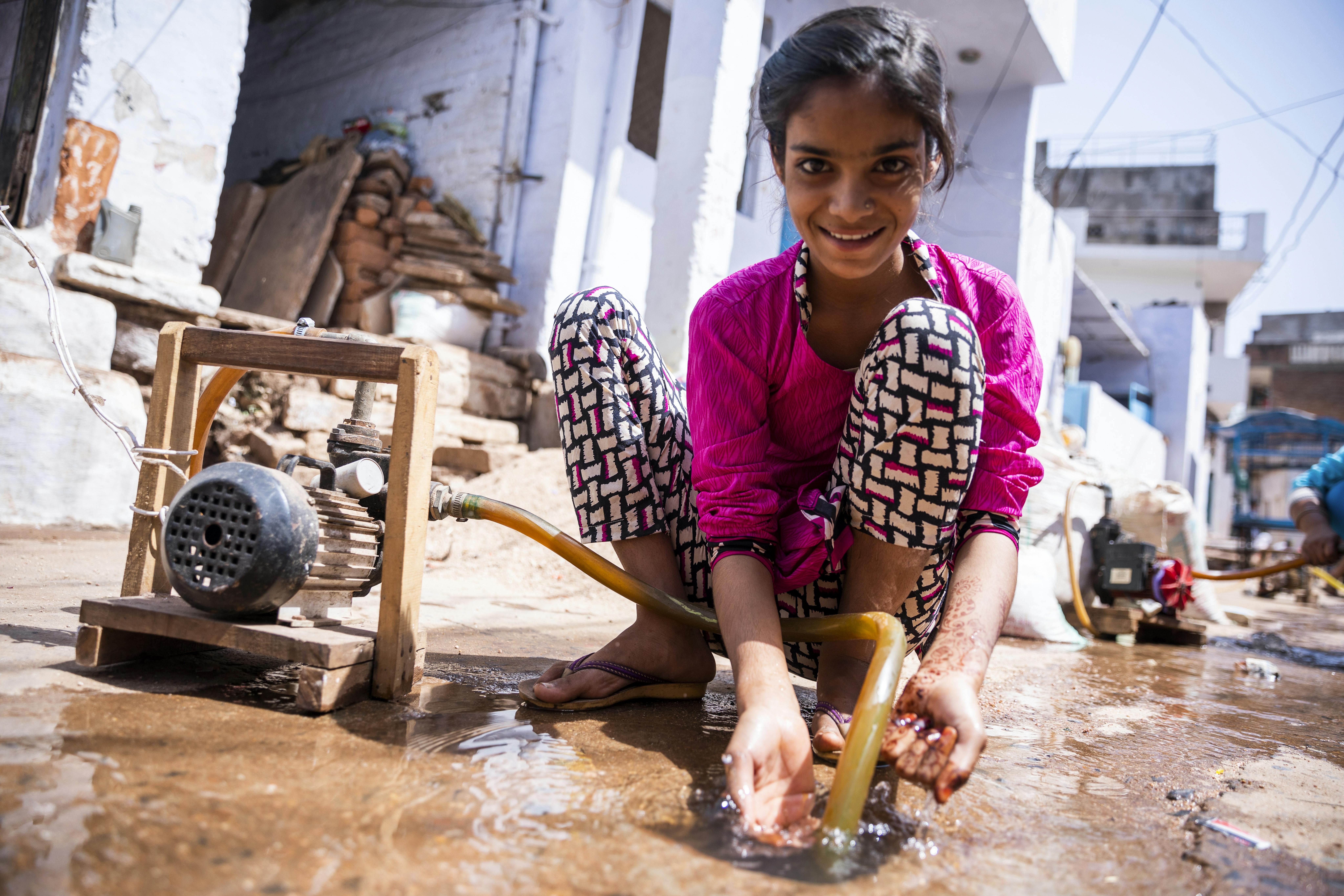 Una bambina raccoglie l'acqua da una pompa a terra presso Shivpuri, in India