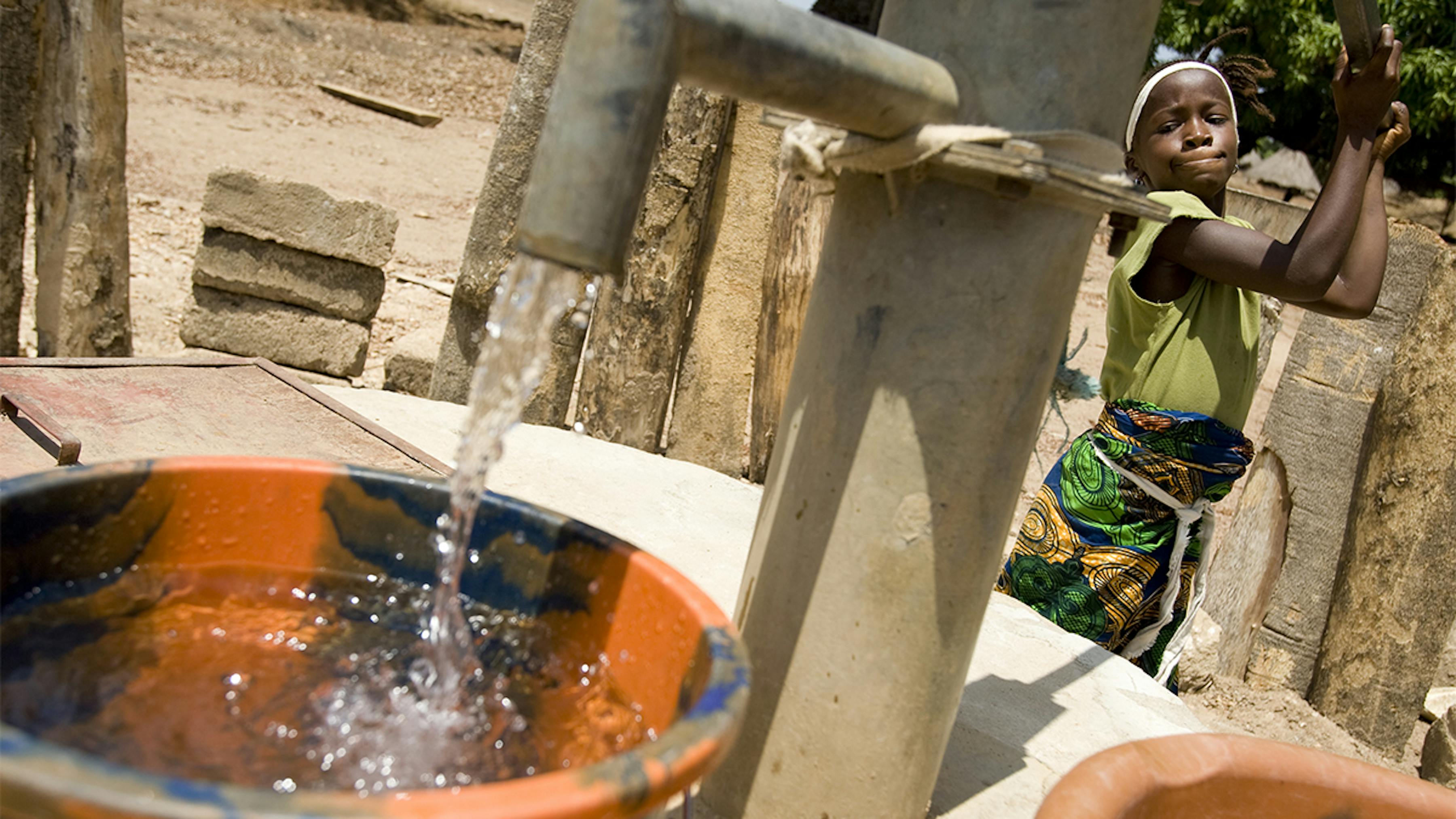 Sierra Leone, una ragazza raccoglie l'acqua presso la pompa a mano della comunità locale