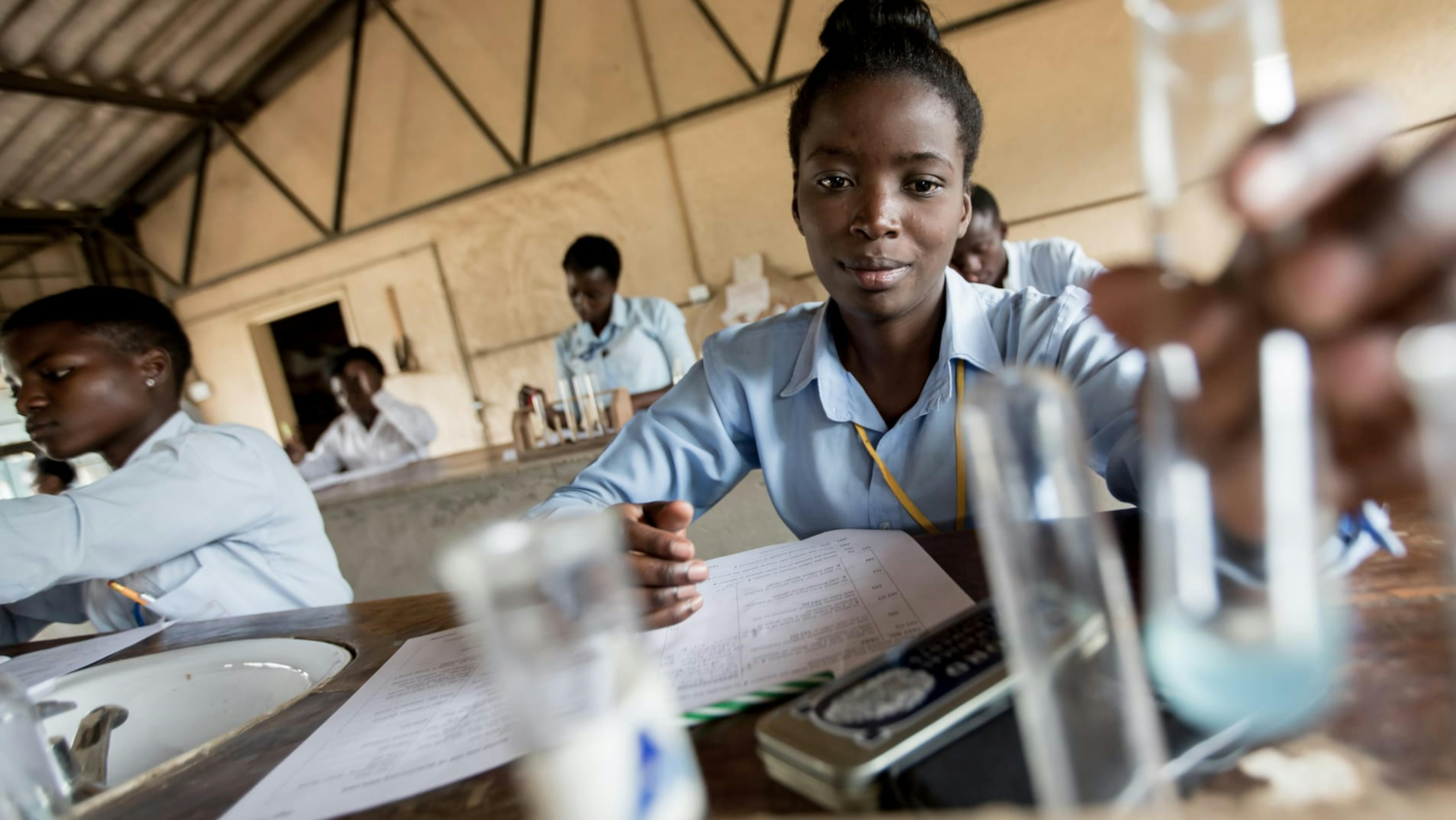 Zambia,una ragazza adolescente conduce un esperimento durante una lezione di chimica.