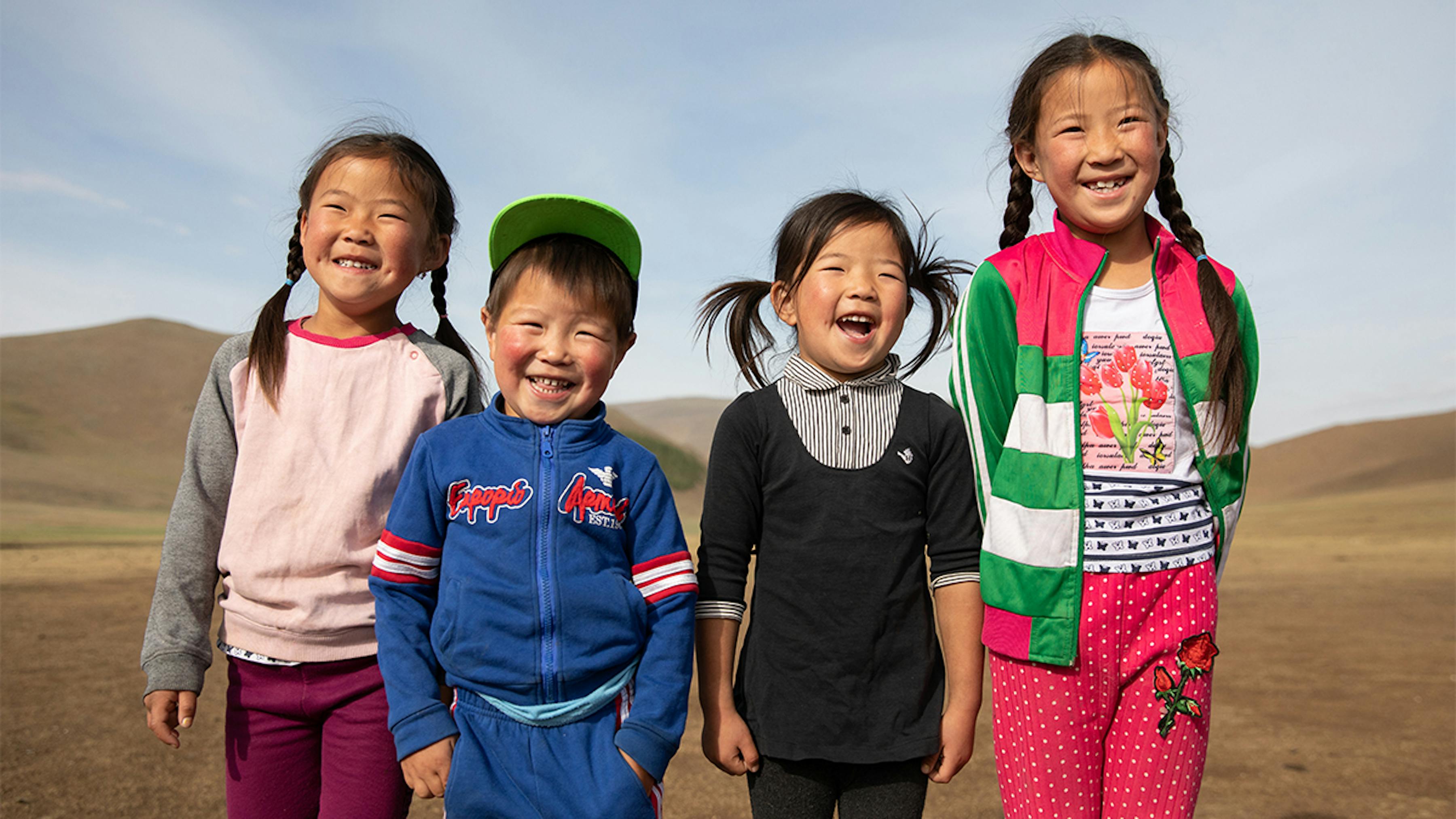 Mongolia, 4 bambini nomadi sorridono: nella zona in cui vivono l'accesso alle scuole è difficile.