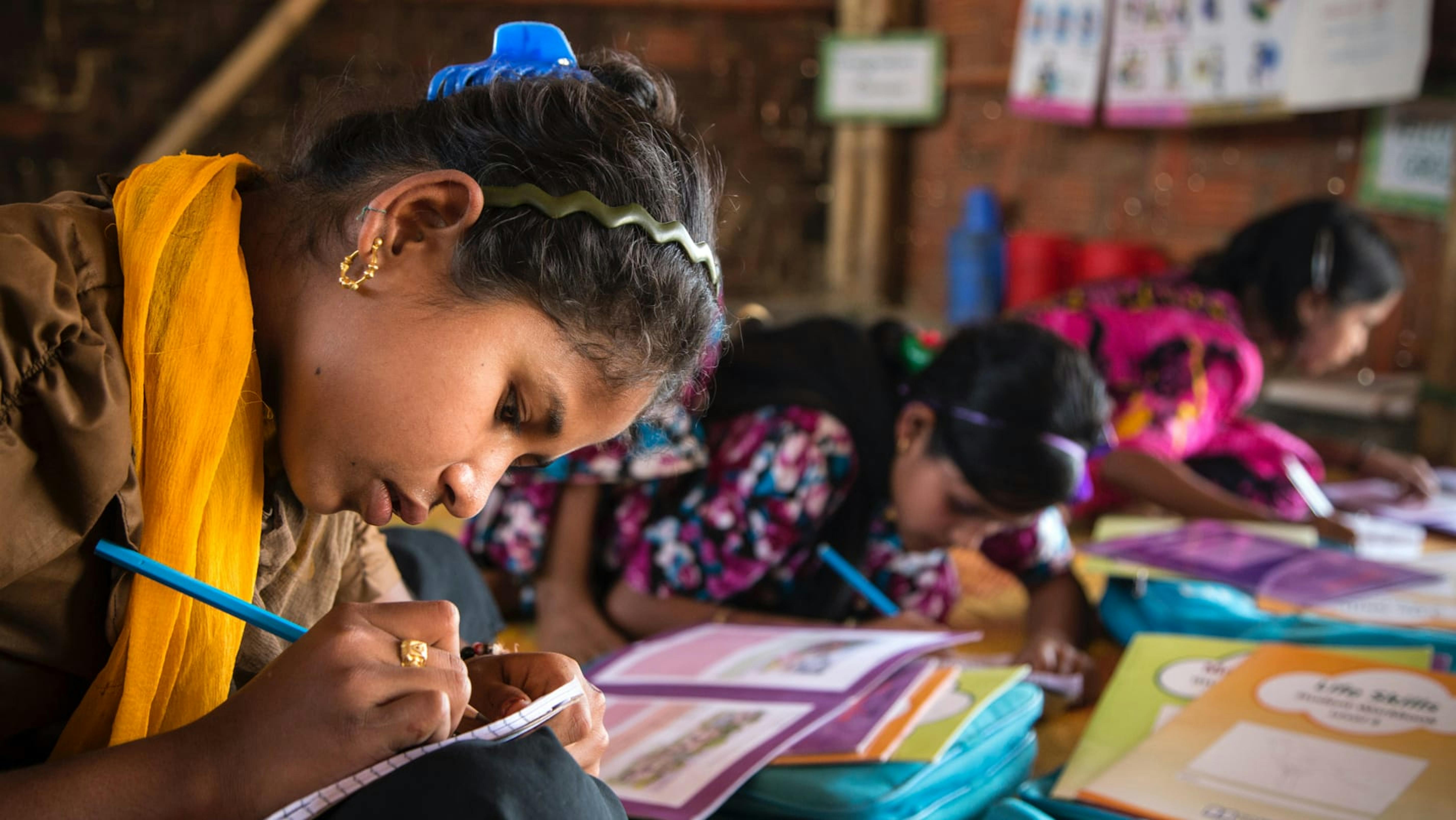 Bangladesh, una ragazza sta studiando in uno spazio per l'apprendimento allestito nel campo rifugiati di Cox's Bazar.