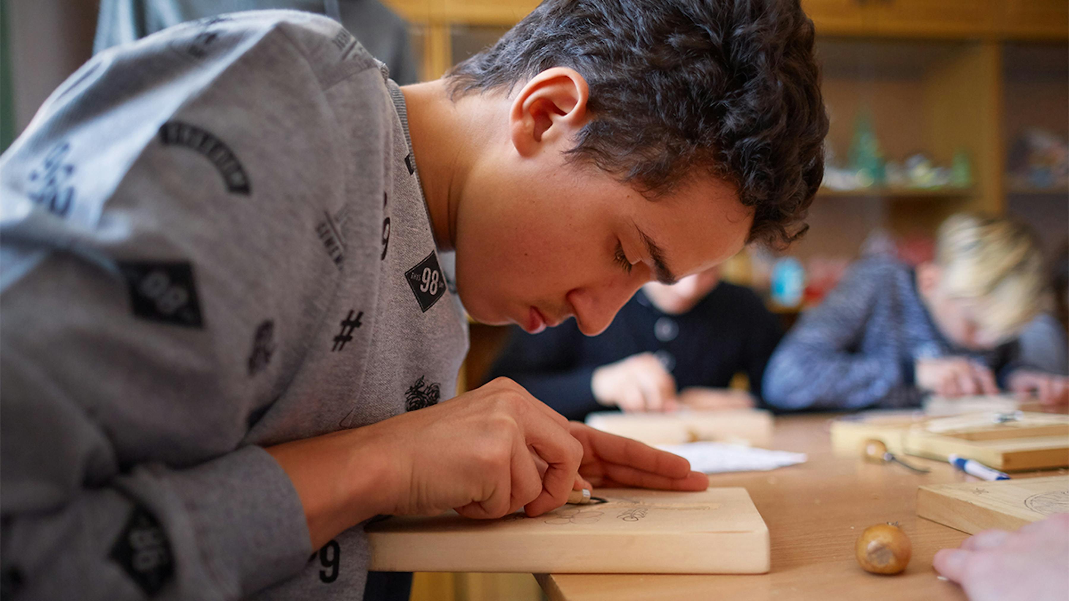 Ucraina, un ragazzo con disabilità uditive alla lezione di scultura in legno.