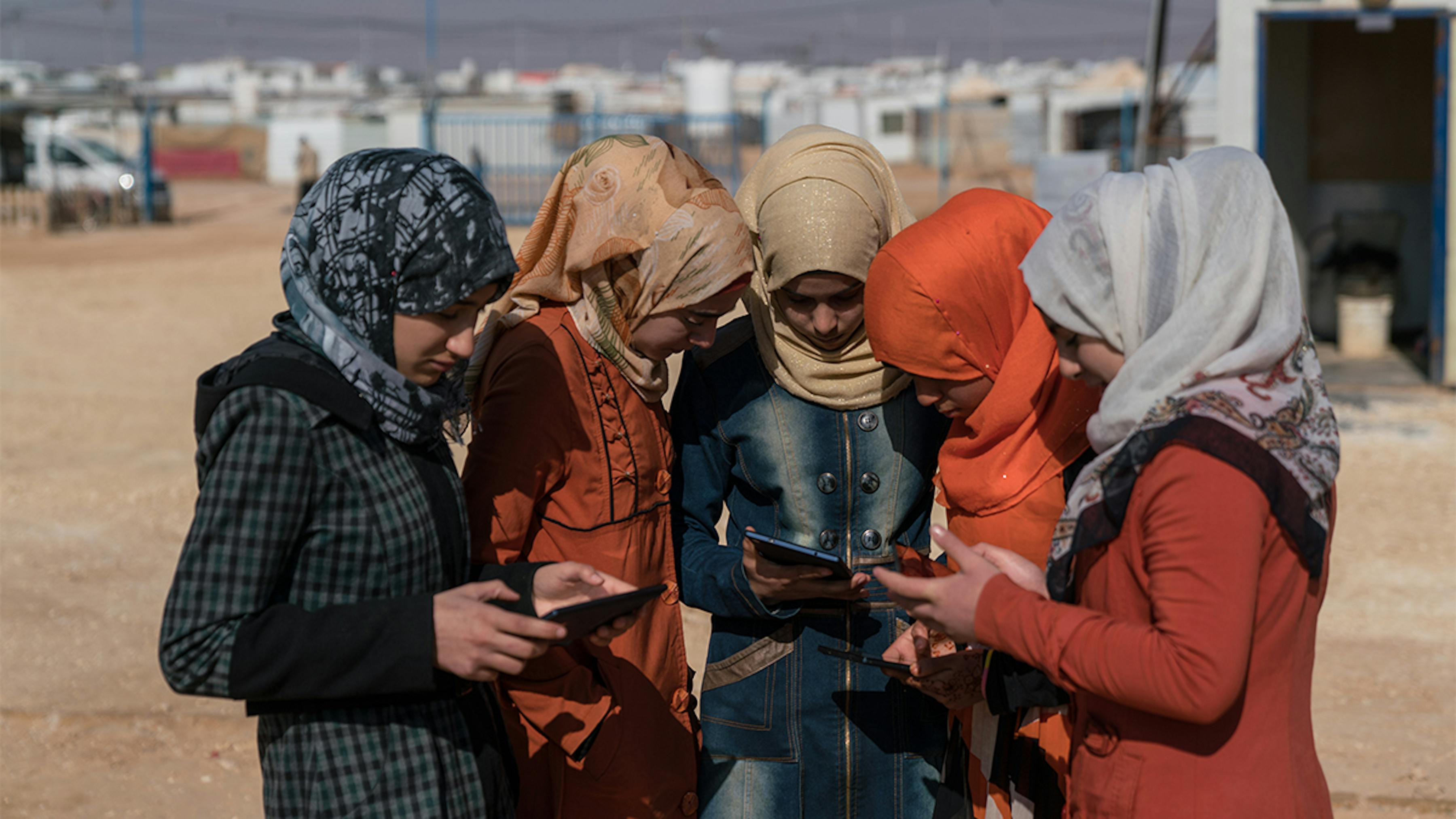 Giordania, ragazze rifugiate siriane con smartphone e tablet per l'apprendimento a distanza.