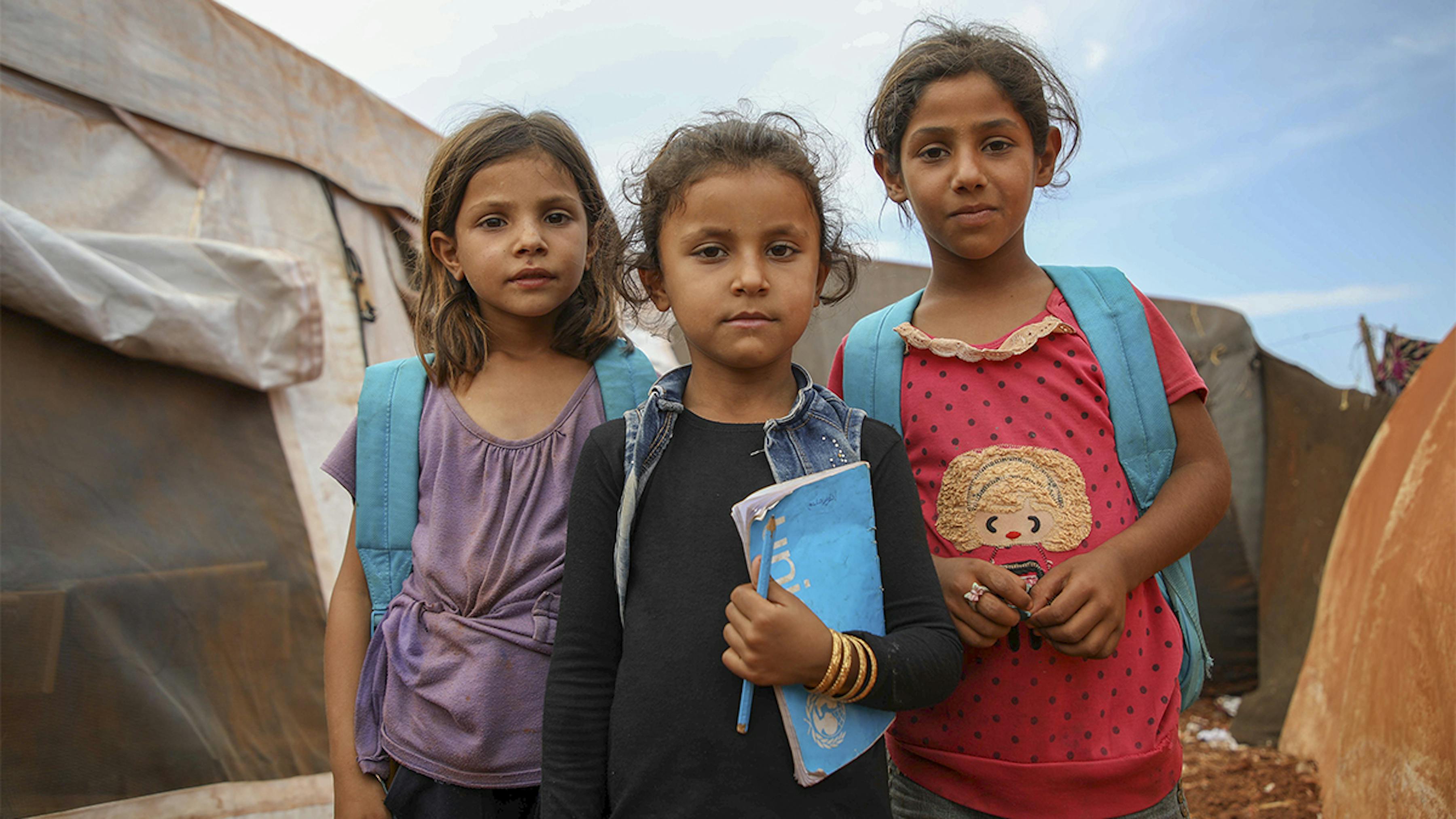 Siria, ragazze con zaini UNICEF fuori da una scuola allestita nel campo rifugiati