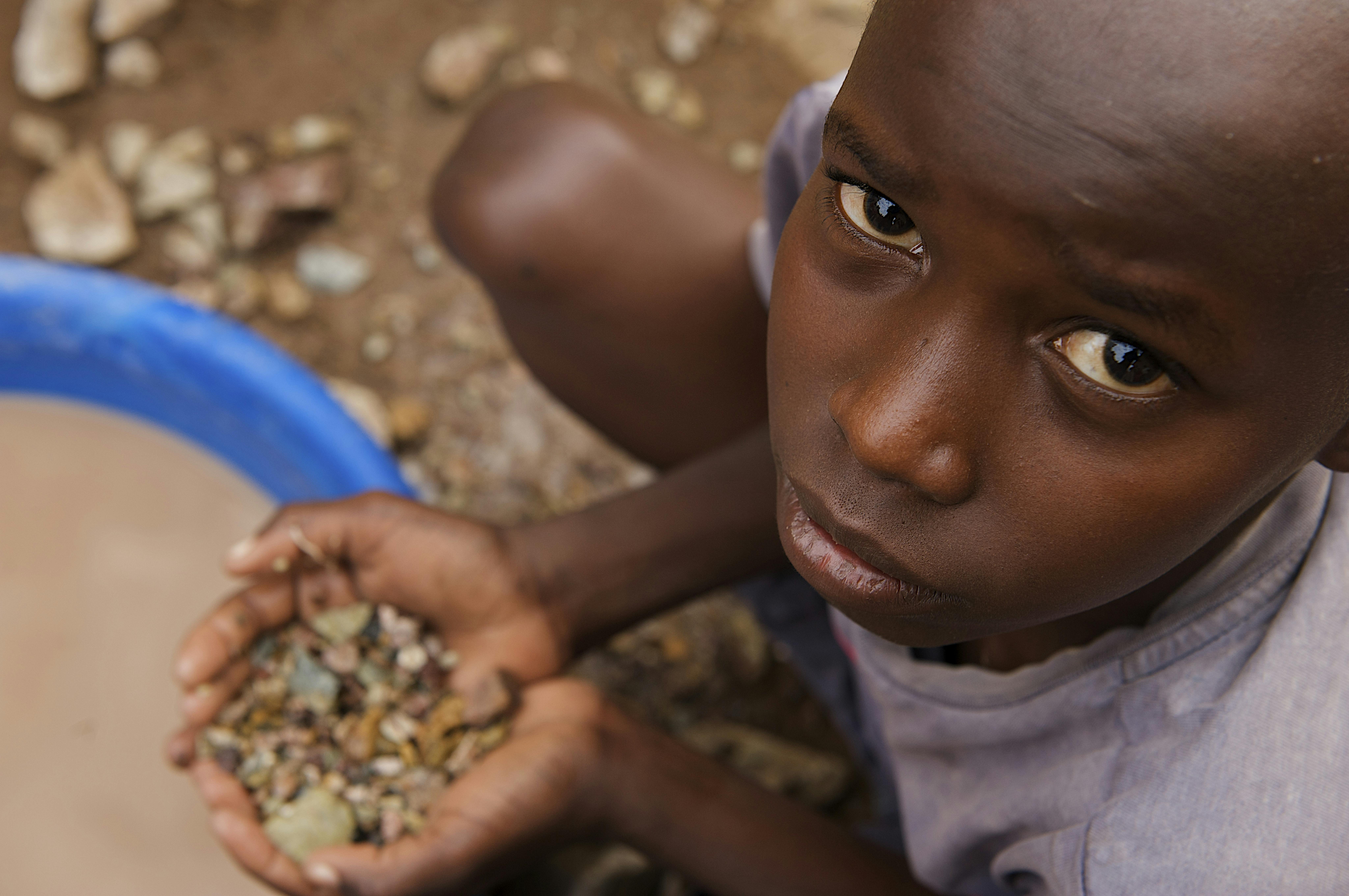 Tanzania, un bambino seduto a cercare oro tra le pietre, nella città mineraria di Nyamongo.