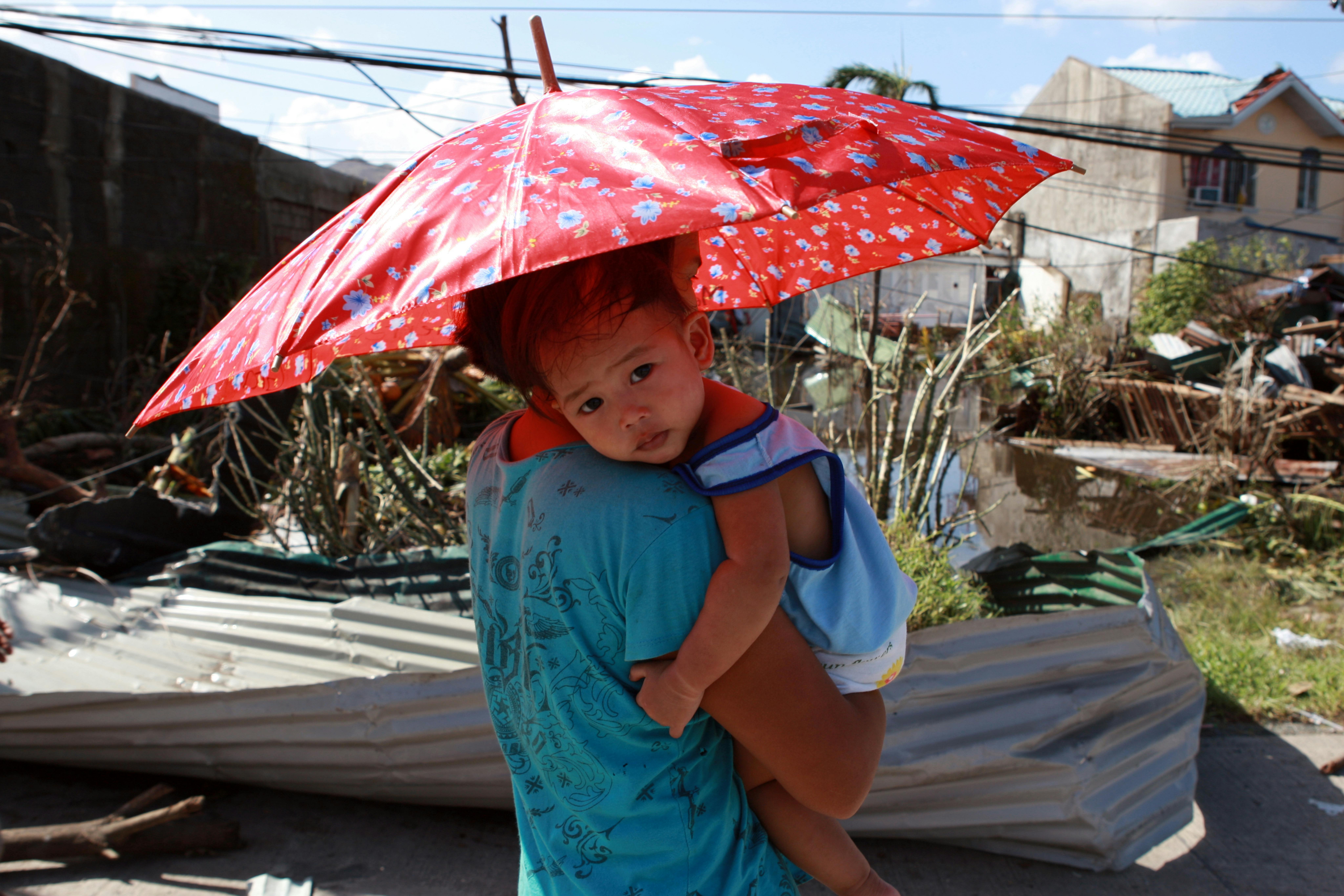 Mamma che abbraccia suo figlio fuori dalla loro casa distrutta dalle piogge in Indonesia