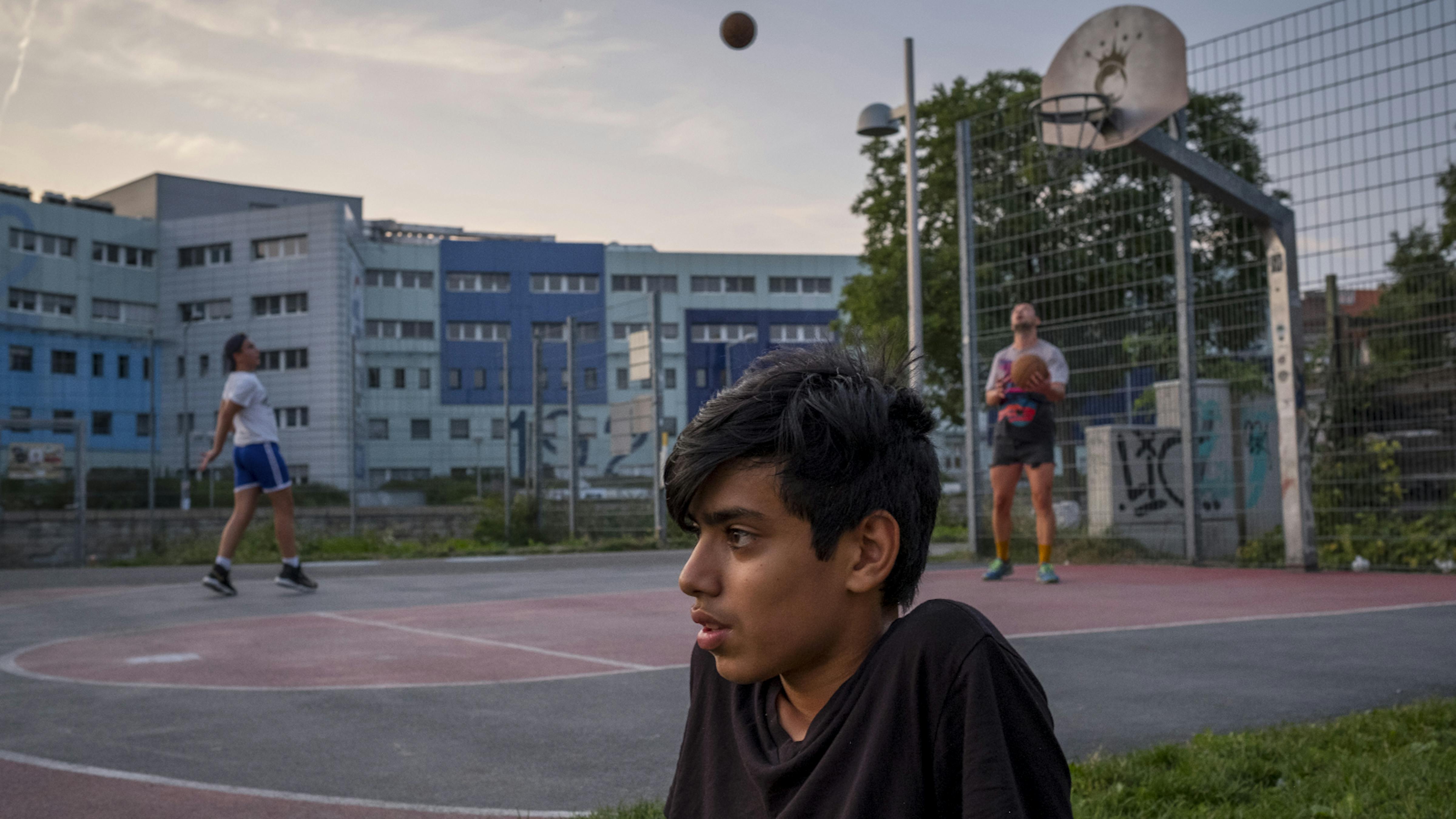 Minore straniero seduto ai margini del campo di basket