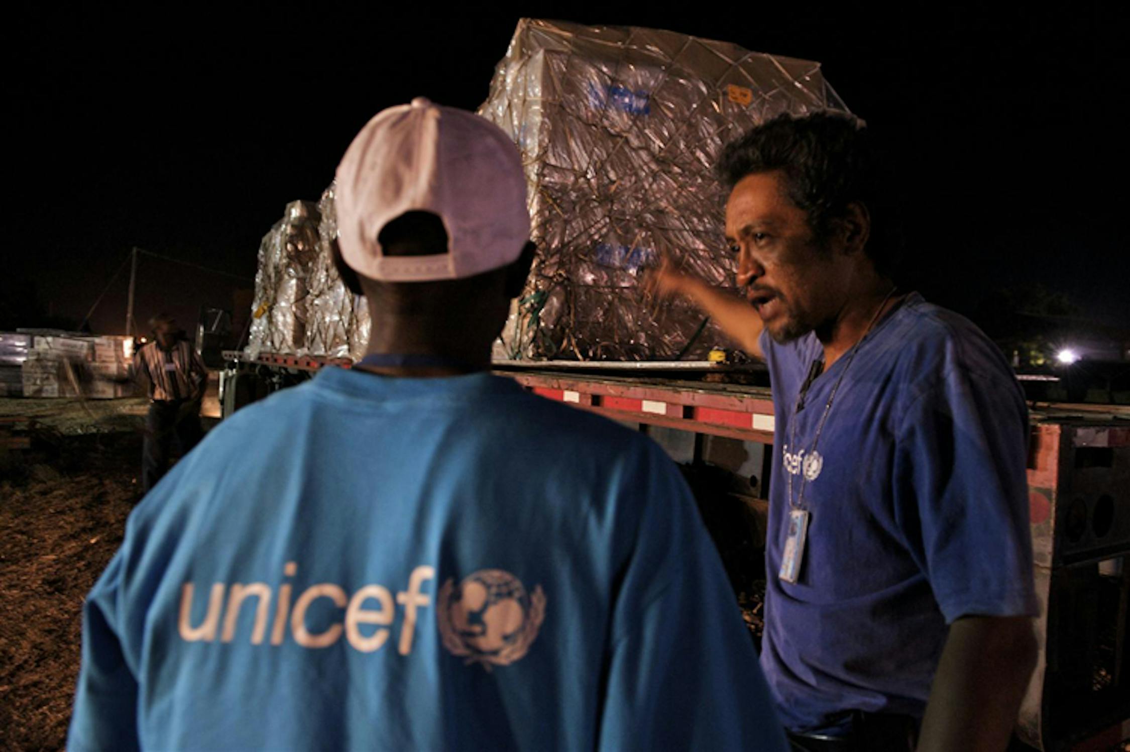 In piena notte, operatori UNICEF nell'aeroporto di Port-au-Prince scaricano beni da un volo umanitario proveniente dagli Stati Uniti