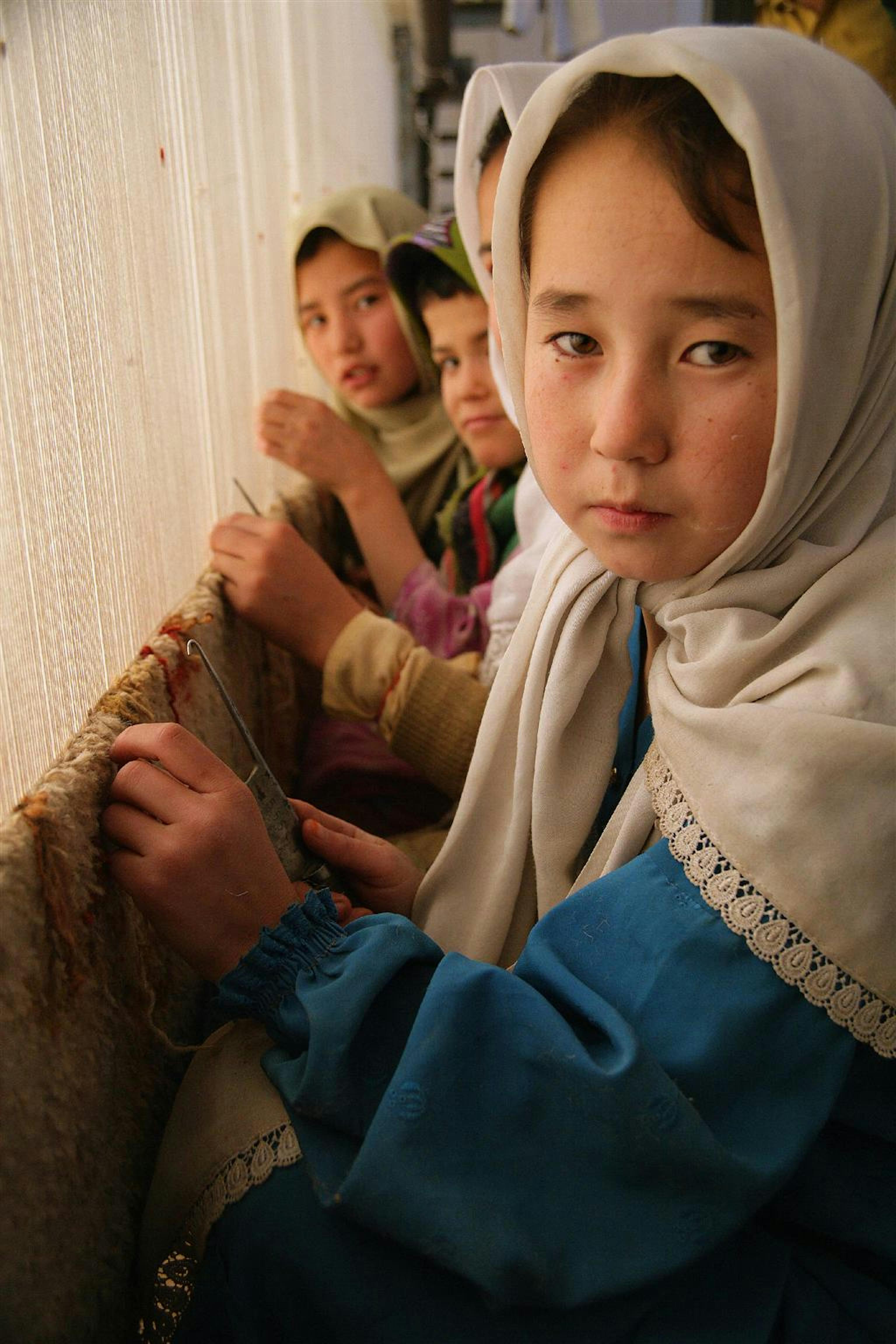 Bambine tessono un tappeto in una grande fabbrica tessile nei dintorni di Quetta, in Pakistan, nonostante nel paese sia illegale lo sfruttamento di manodopera minorile - ©UNICEF/HQ06-0350/G.Pirozzi
