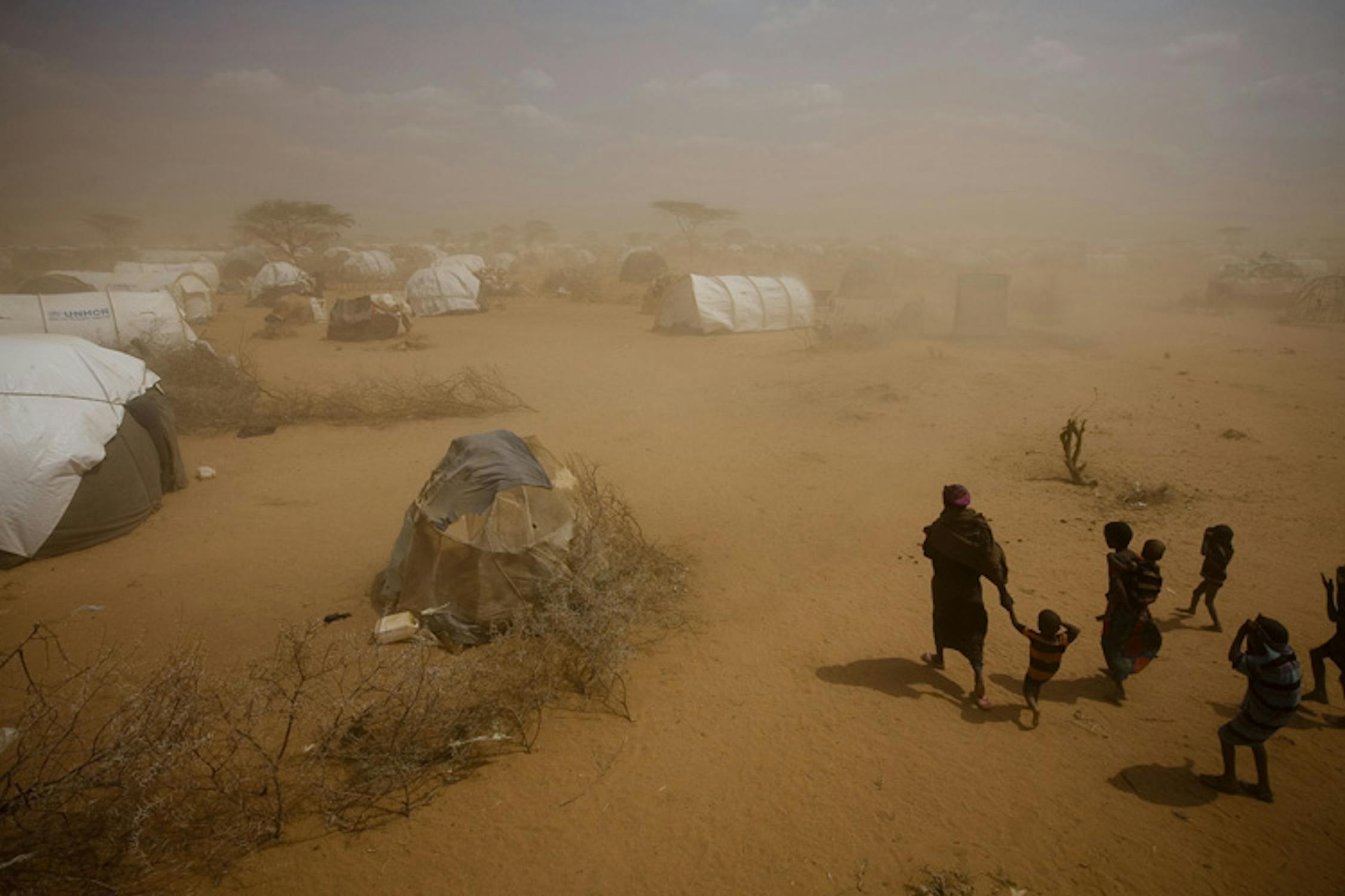 Una donna con i suoi figli avanza in una tempesta di sabbia nel campo profughi di Dagahaley, al confine tra Kenya e Somalia - ©UNICEF/NYHQ2011-1019/K.Holt