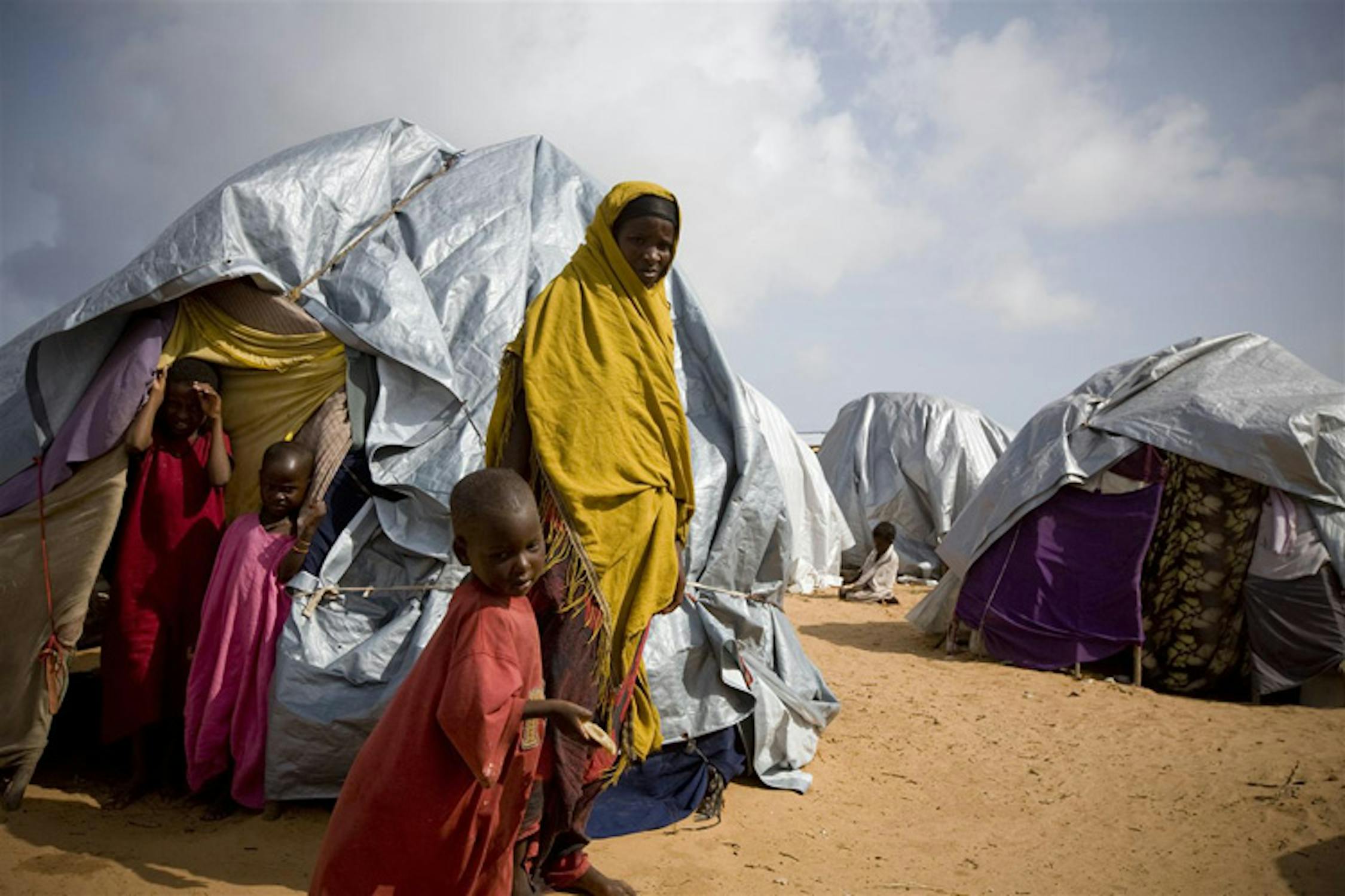 Una donna e i suoi figli accanto alla sua tenda nel campo per sfollati di Badbado, presso Mogadiscio (Somalia). In queste condizioni vivono circa 30.000 persone, in maggioranza donne e bambini - ©UNICEF/NYHQ2011-1185/K.Holt