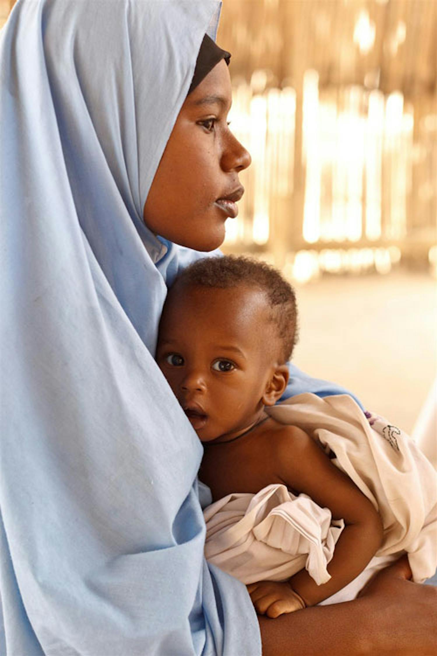 Farida, 16 anni, tiene in braccio il fratellino Laouli, 9 mesi, che attende di essere visitato in un centro nutrizionale terapeutico nella città di Mirriah (Niger) - ©UNICEF/NYHQ2012-0176/Asselin
