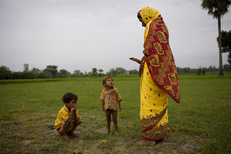 Una donna osserva i suoi bambini mentre defecano in un campo - ©UNICEF India/2008-0065/Adam Ferguson