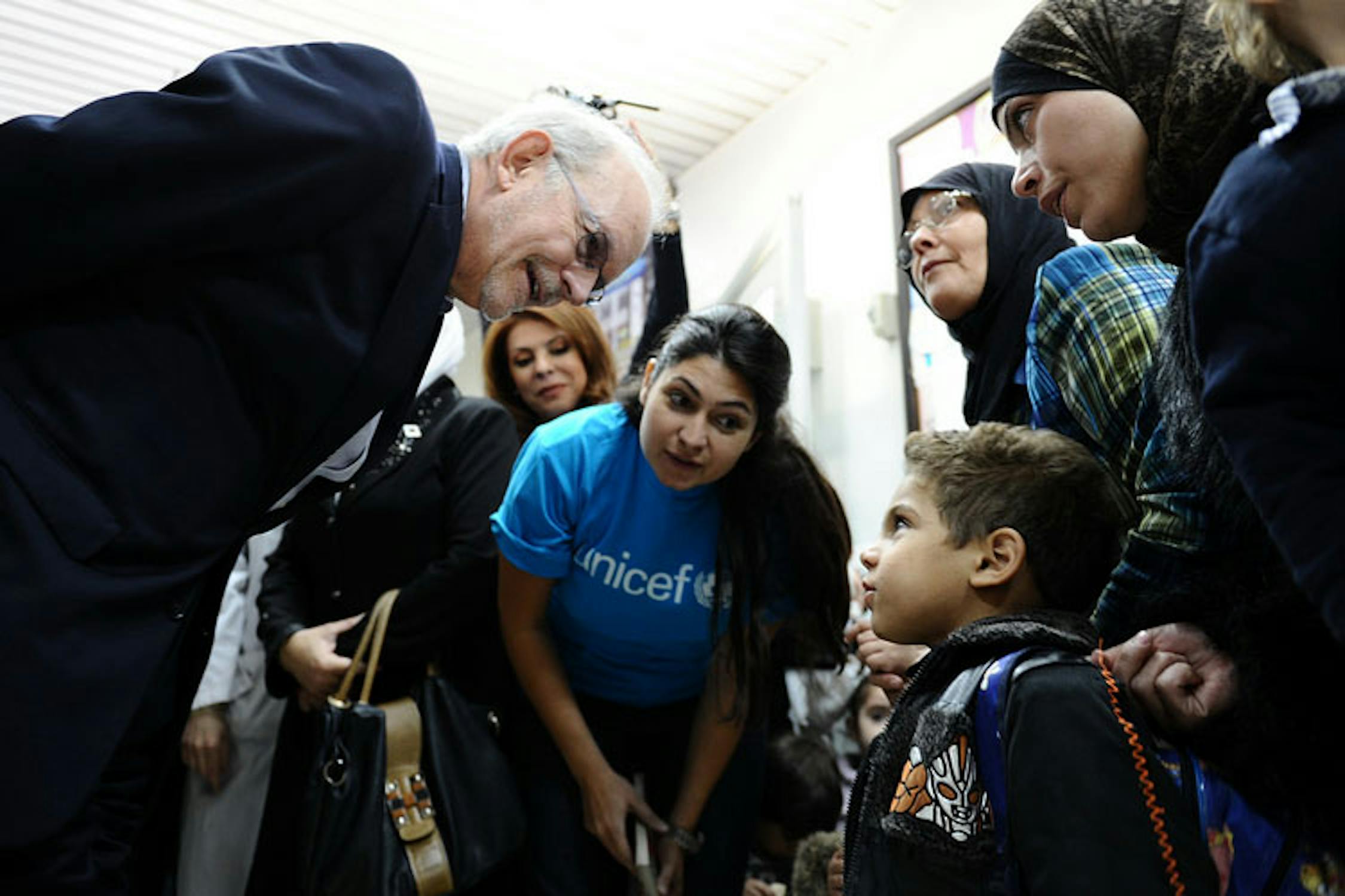 Il direttore UNICEF Anthony Lake parla con un bambino che attende di essere vaccinato nell'ambulatorio di Abu Dhar Al-Ghifari, a Damasco - ©UNICEF/NYHQ2013-0922/Sanadiki