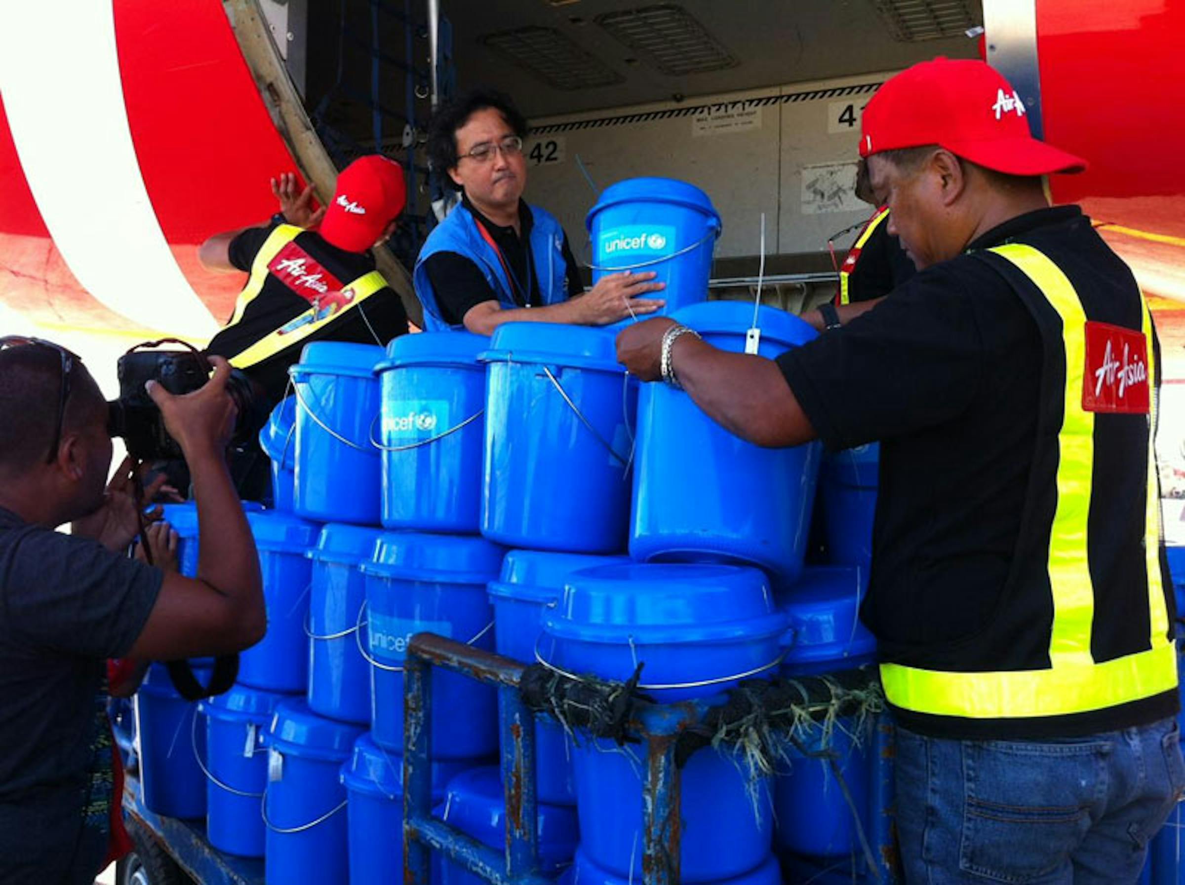 Il Rappresentante UNICEF nelle Filippine Tomoo Hozumi e alcuni operatori caricano scorte di aiuti sul charter umanitario donato a UNICEF da AirAsia - ©UNICEF/PFPG2013P-0246/Marissa Aroy