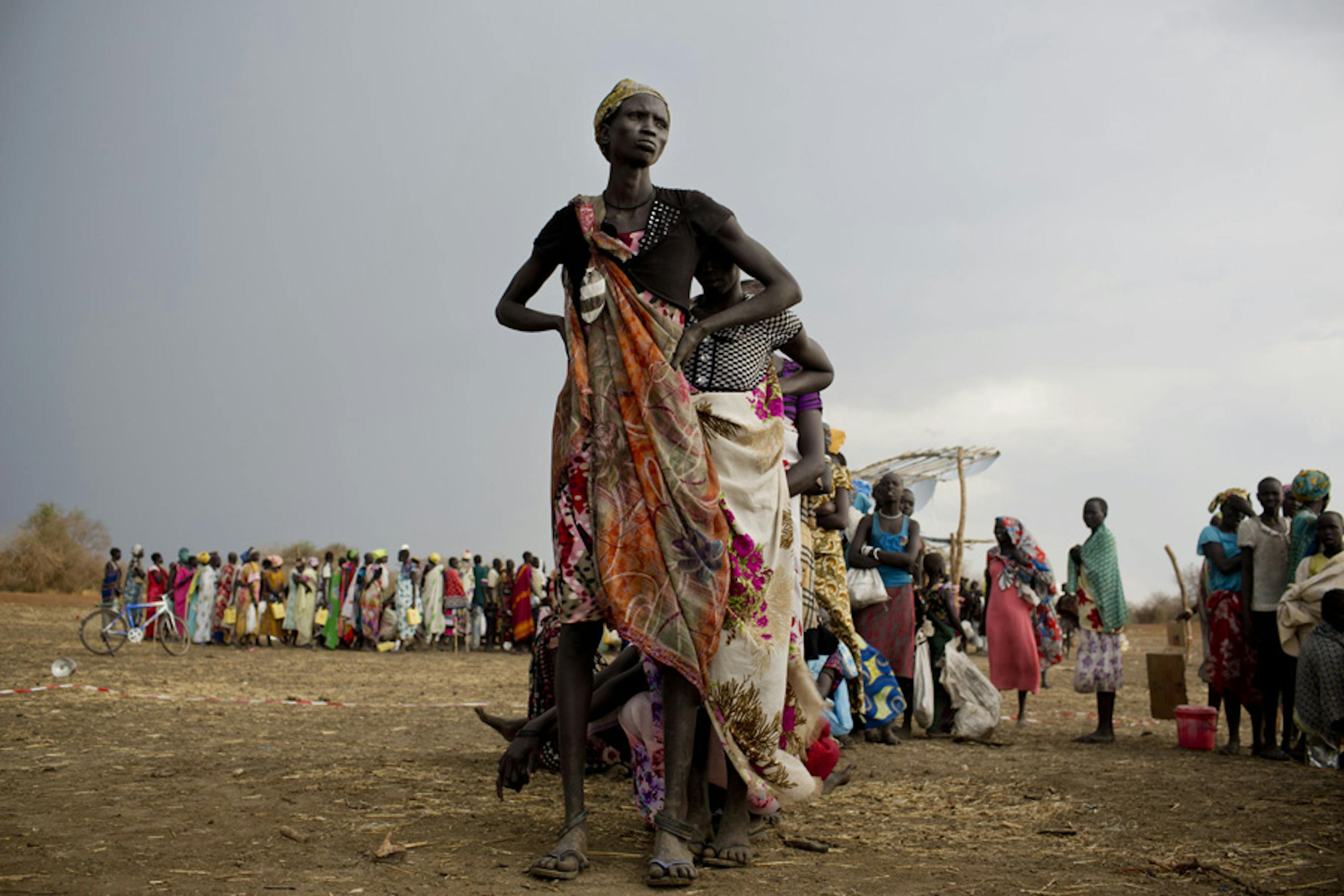 Donne e bambini fanno la fila per la distribuzione di razioni alimentari in un punto di distribuzione di aiuti alimentari a Mingkaman (Sud Sudan) - ©UNICEF/NYHQ2014-0349/Holt