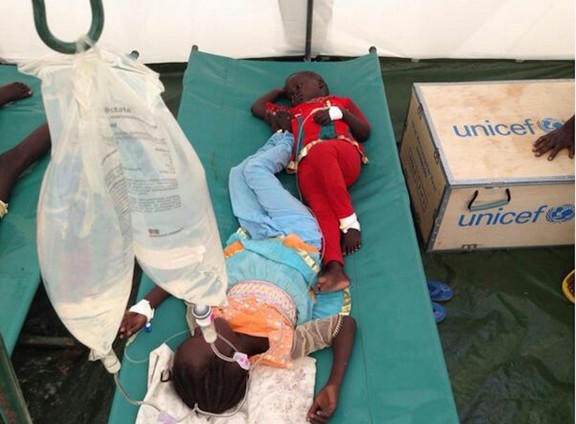 Due sorelline di 4 e 7 anni ricevono la fluidoterapia per la cura del colera all'interno di una tenda-ospedale allestita dall'UNICEF a Juba (Sud Sudan) - ©UNICEF/2014/Kent Page