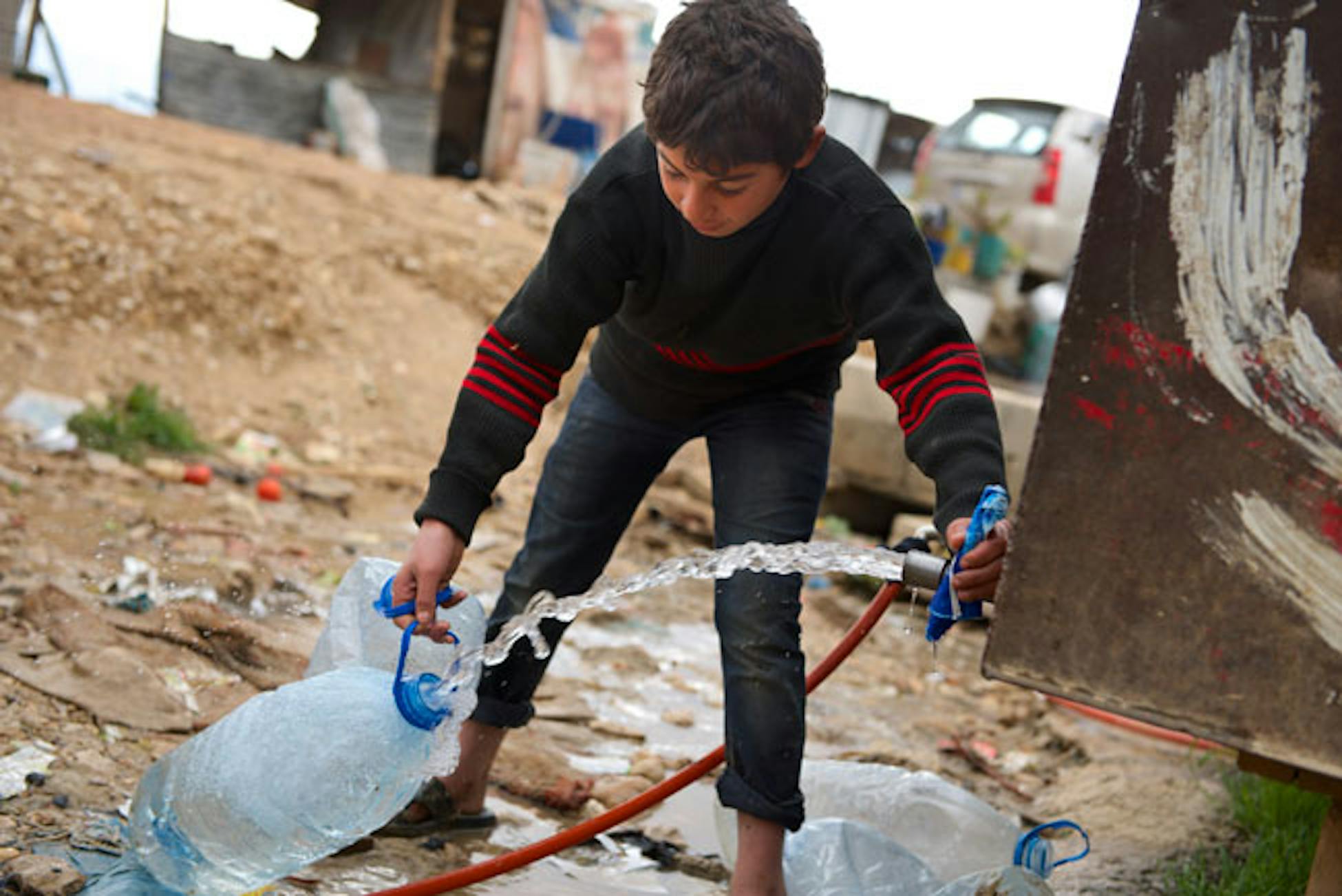 Un bambino riempie una tanica di acqua dalla cisterna installata dall'UNICEF nel campo profughi di Baalbek (Libano) - ©UNICEF Libano/2013/Shehzad Noorani