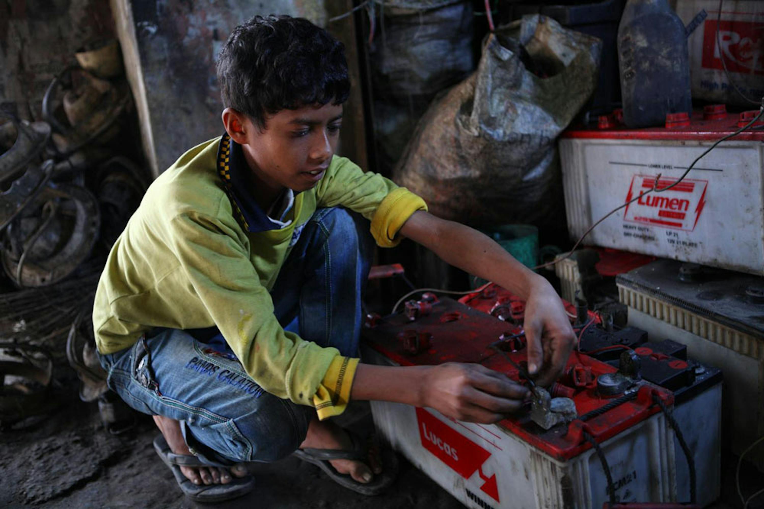Al Amin, 10 anni, ripara le batterie degli autobus in un garage della stazione dei bus di Tangail (Bangladesh) - ©UNICEF Bangladesh/2014-00249/Shafiqul Alam Kiron