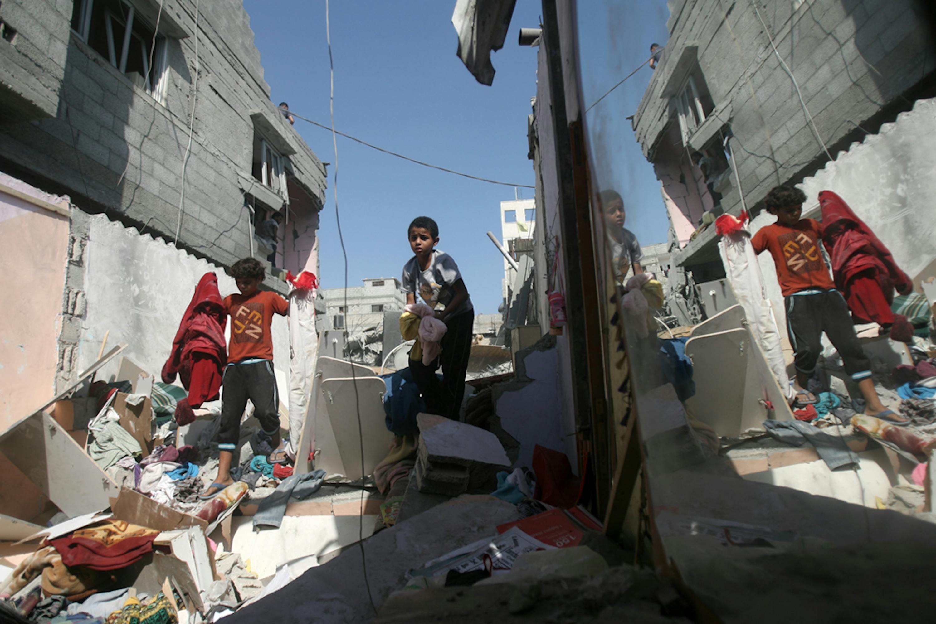 Bambini palestinesi recuperano alcuni vestiti dalle macerie della loro abitazione nel campo profughi di Khan Younis, nel sud della Striscia di Gaza - ©UNICEF/NYHQ2014-0905/Iyad El Baba