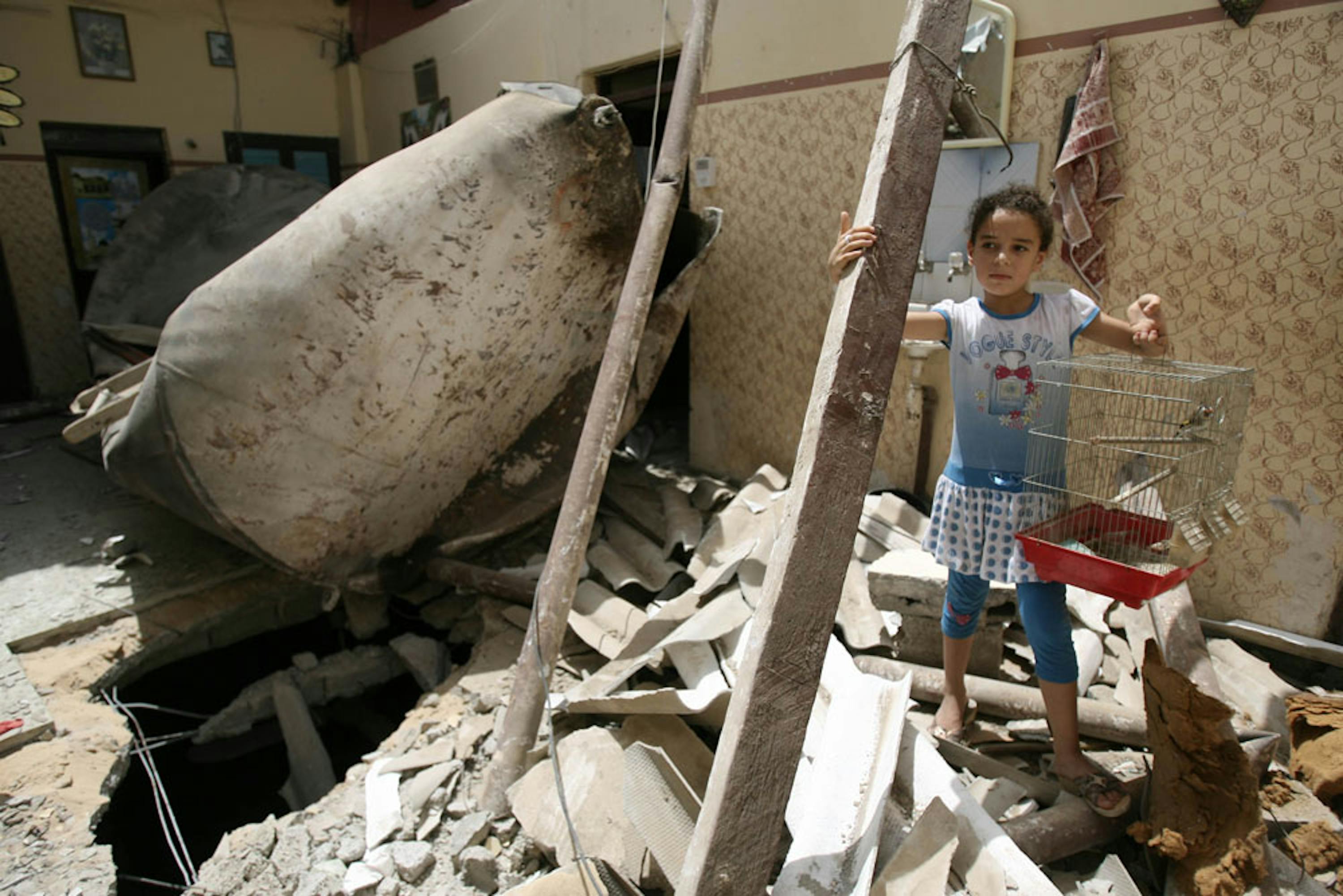 Una bambina di Rafah (nel sud della Striscia di Gaza) recupera una gabbia per uccellini dalle macerie della sua casa, distrutta da un raid aereo israeliano - ©UNICEF/NYHQ2014-0911/Eyad El Baba