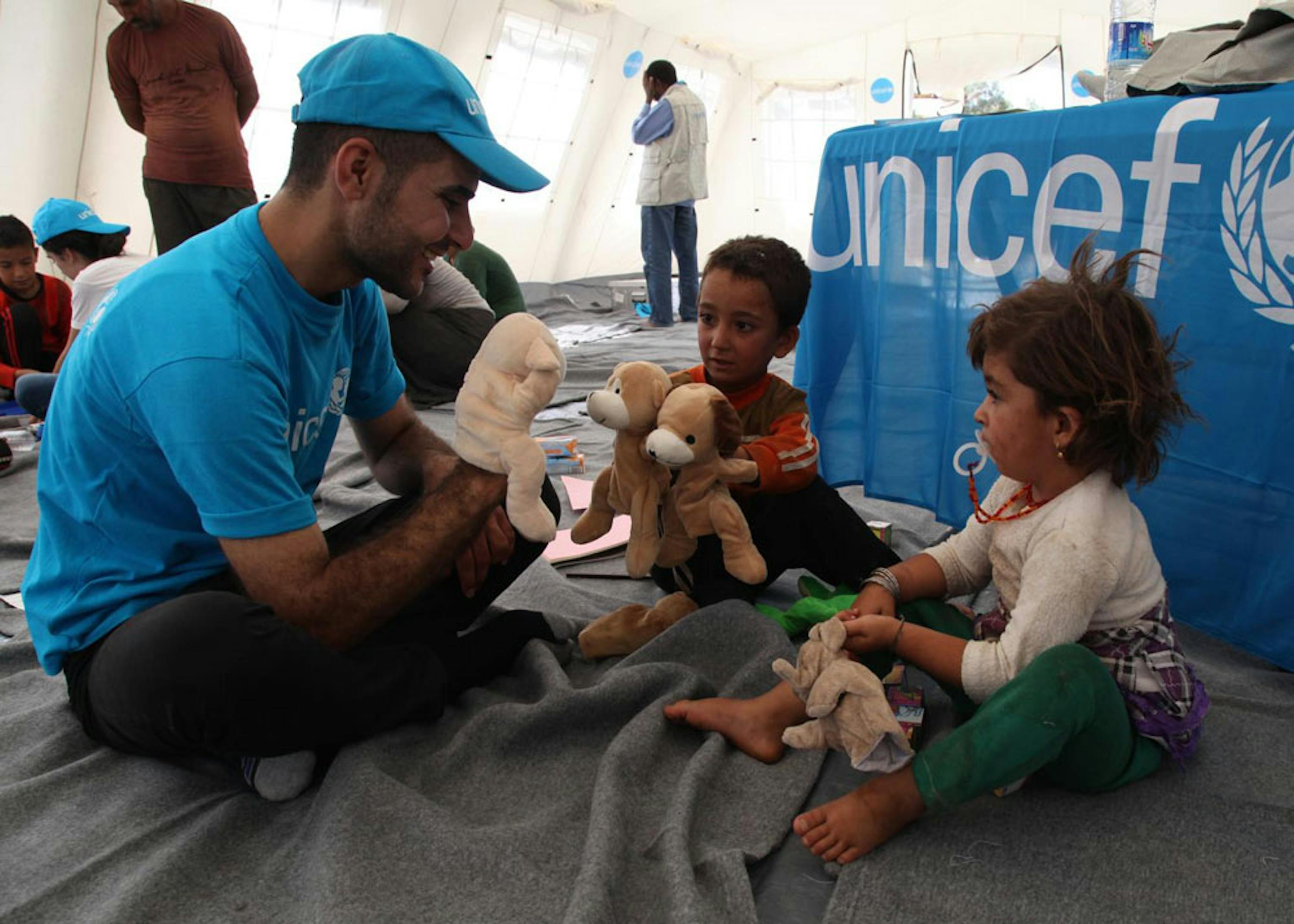 Un operatore UNICEF gioca con due bambini in un centro per sfollati a Peshkhabaour (Iraq). Quasi 4 milioni di bambini di questa età sono stati vaccinati contro la polio in soli 5 giorni - ©UNICEF/NYHQ2014-1177/Khuzaie