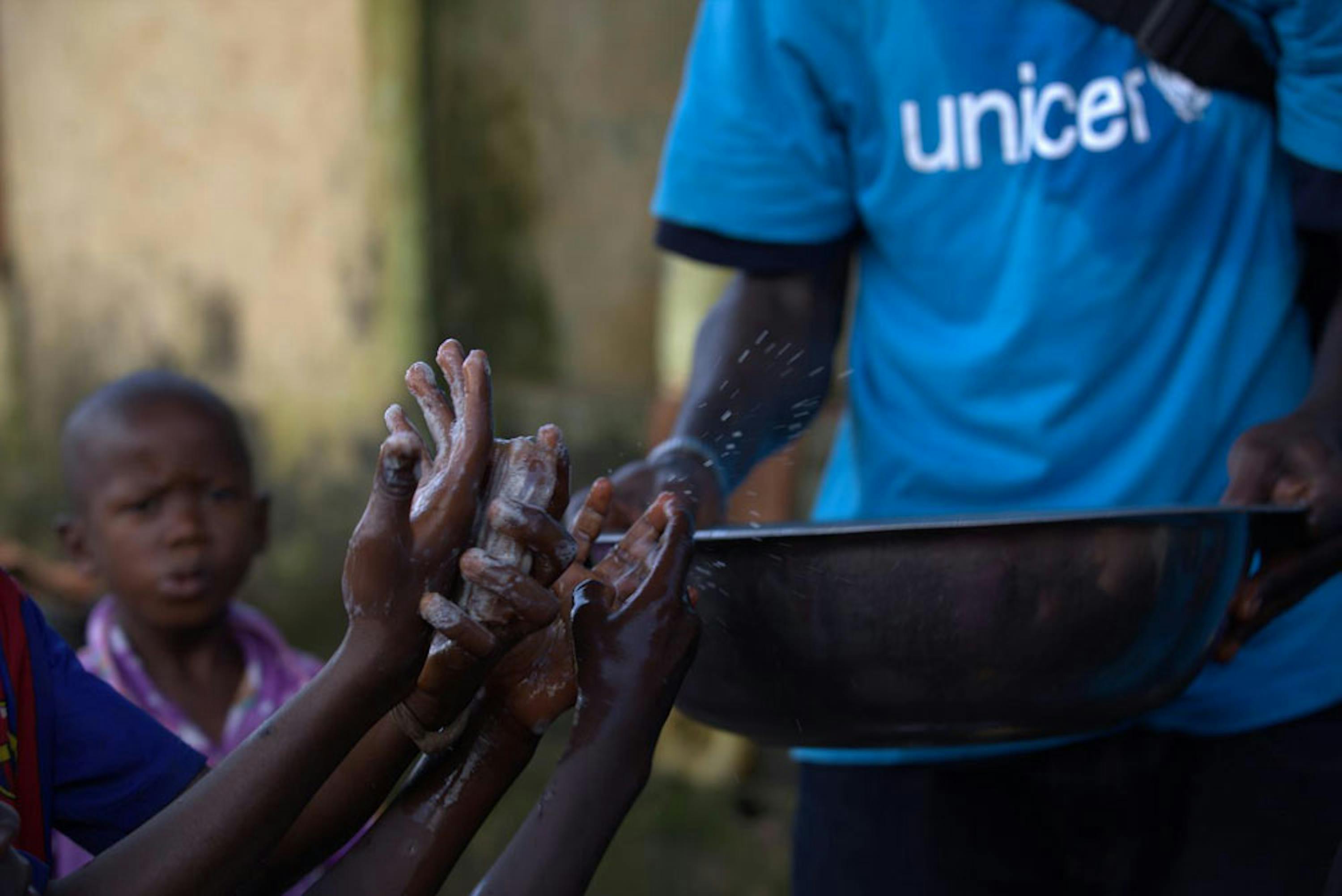 Un volontario di un'associazione locale partner dell'UNICEF impegnato in un'attività di educazione all'igiene con i bambini a Conakry (Guinea) - ©UNICEF/NYHQ2014-1522/LaRose