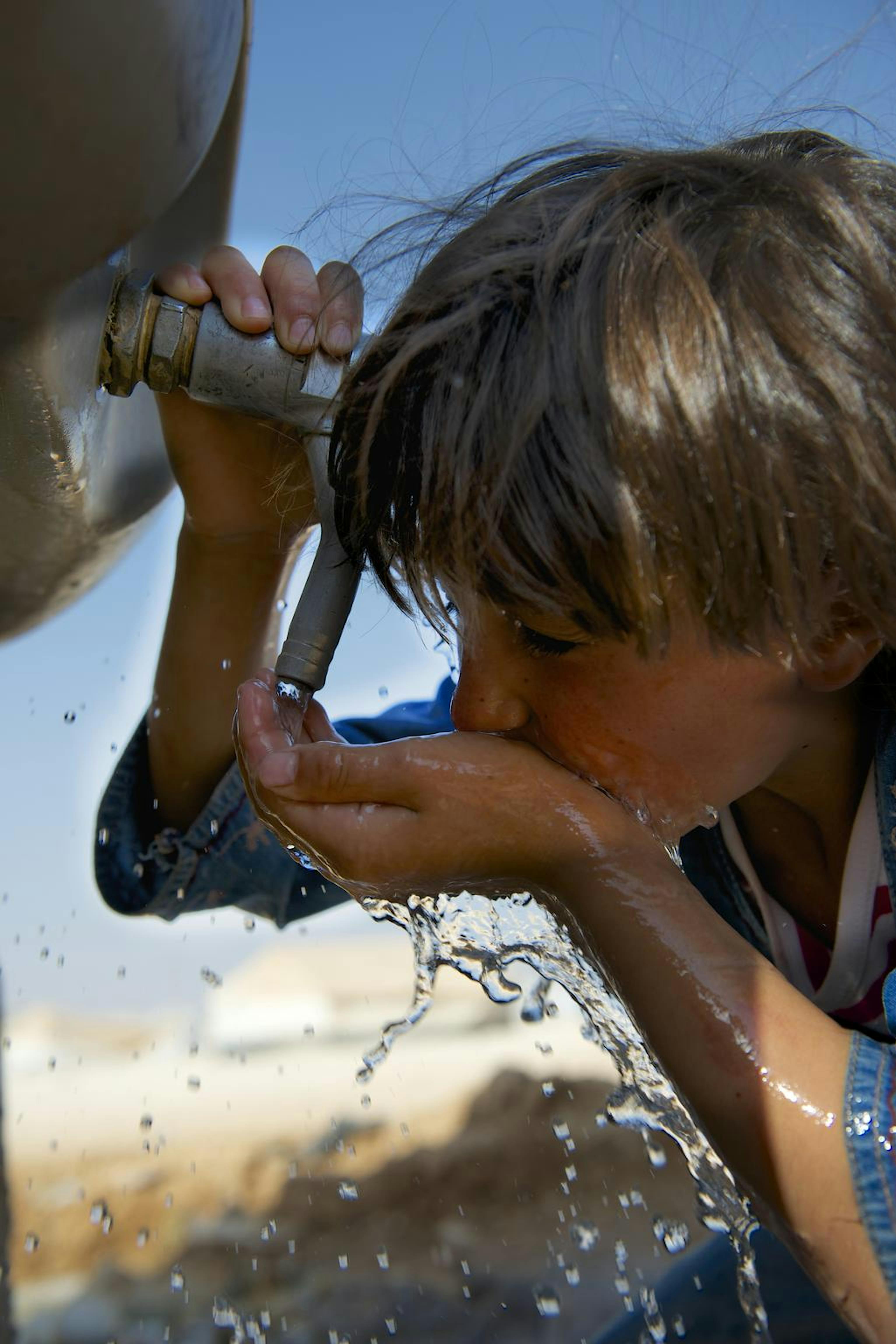 Una bambina siriana si disseta da una cisterna installata dall'UNICEF nel campo profughi di Za'atari, in Giordania - ©UNICEF/NYHQ2013-0667/Noorani