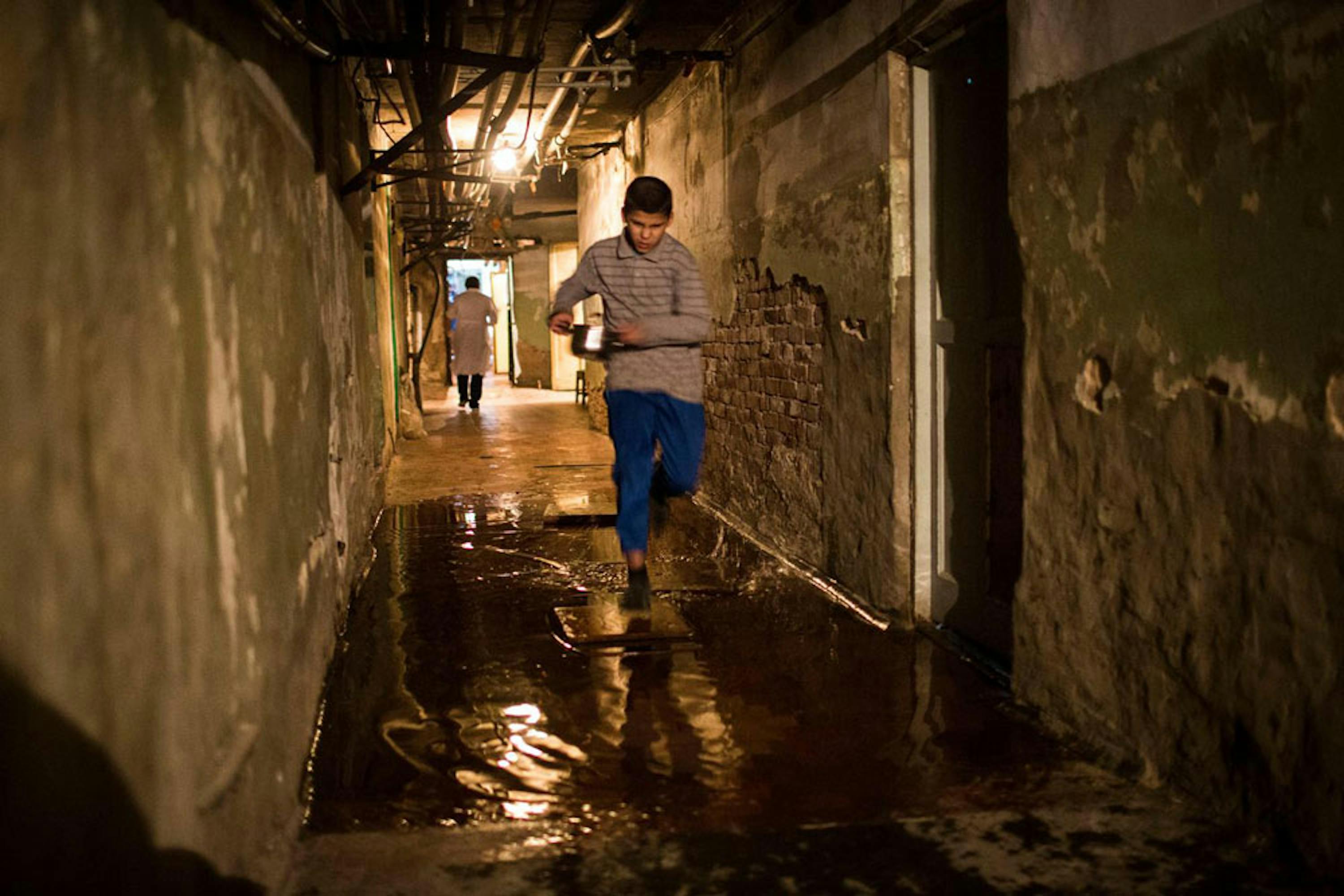 Un ragazzo trasporta di corsa il pasto della sua famiglia, che da mesi vive nei sotterranei di un palazzo a Donetsk con gravissimi problemi igienici e di umidità - ©UNICEF/NYHQ2014-3505/Francesca Volpi