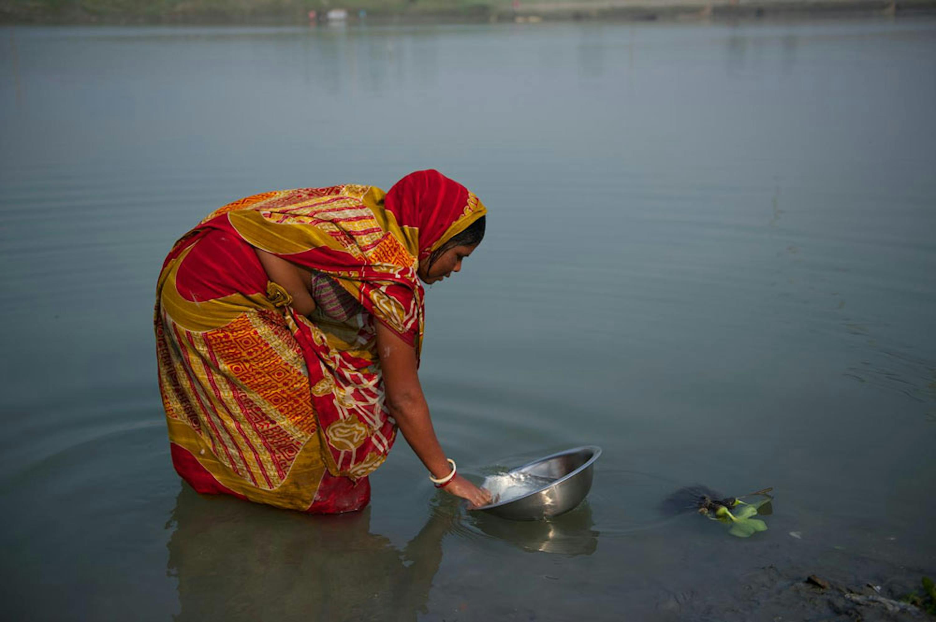 Una donna lava le stoviglie in un fiume del distretto di Jamalpur, Bangladesh - ©UNICEF/NYHQ2014-3287/Noorani