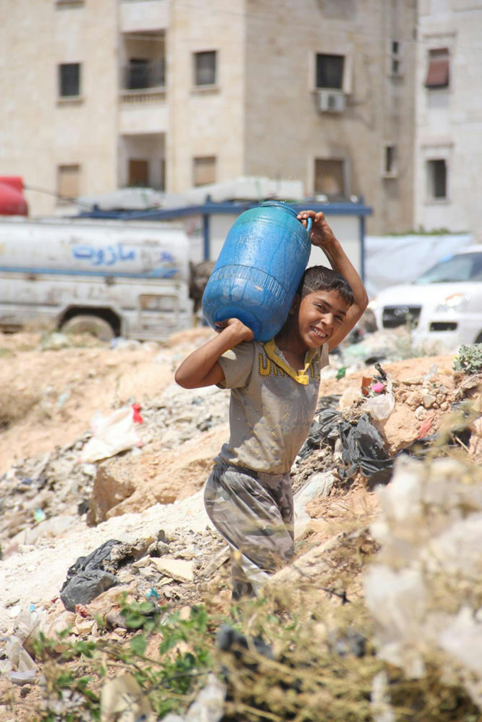 Un bambino trasporta un bidone di acqua a Tishreen, un campo per sfollati nella città di Aleppo (Siria) - ©UNICEF/NYHQ2014-3061/Rashidi