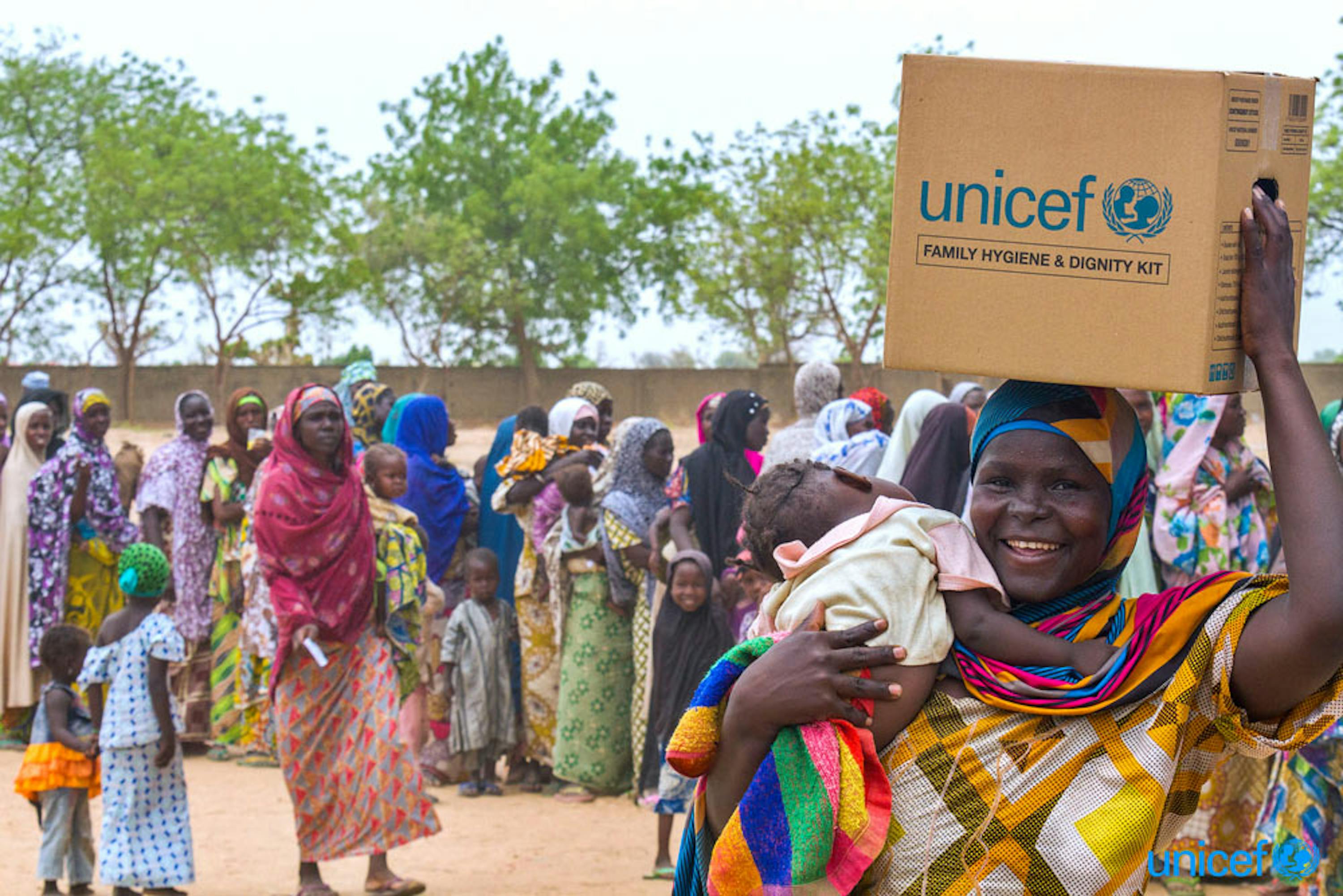 Una donna con un kit per l'igiene familiare che ha appena ricevuto  nel campo per sfollati di Maiduguri, Nigeria © UNICEF/UNI193739/Esiebo