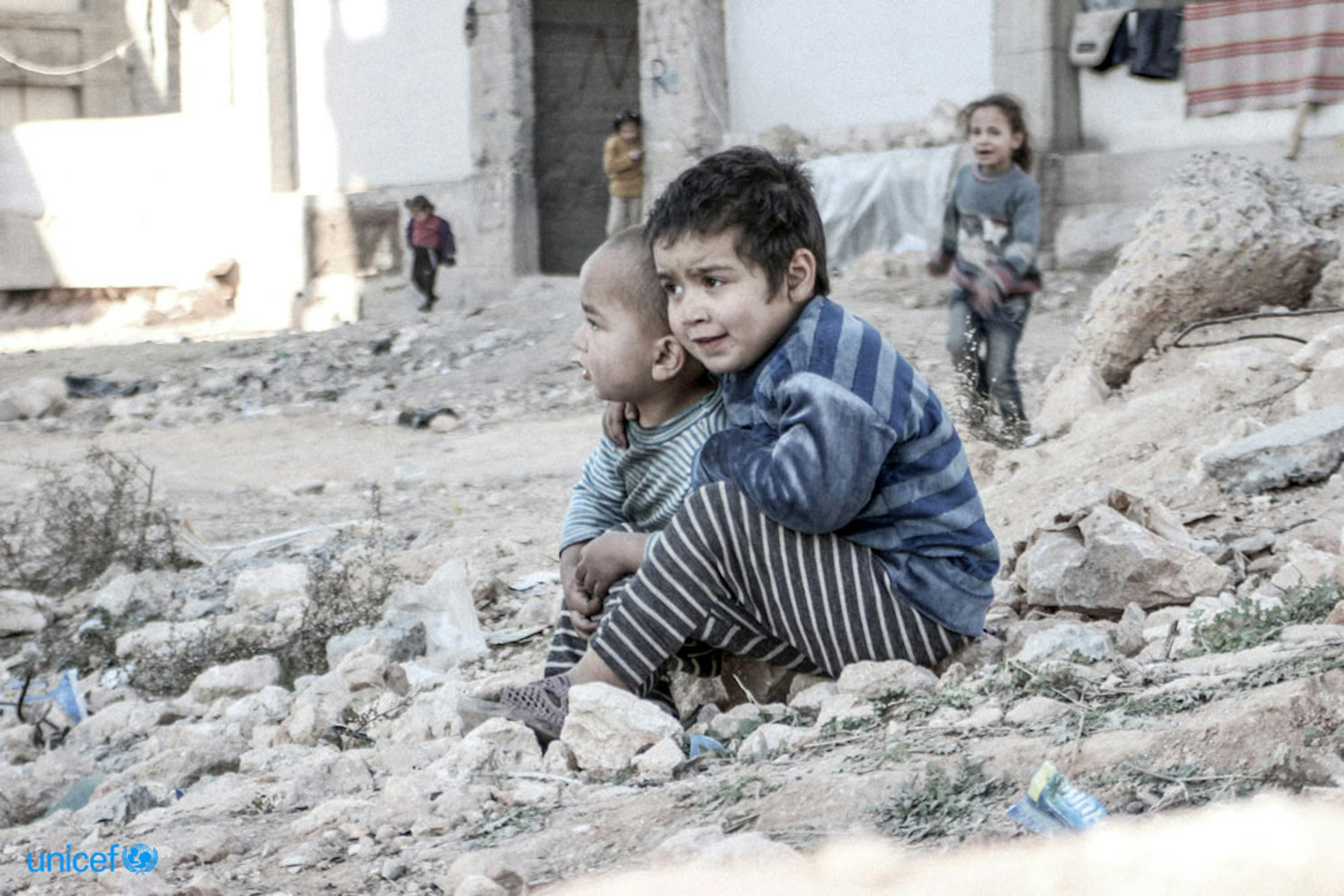 Due bambini seduti tra le macerie  © UNICEF/UN013175/Al-Issa