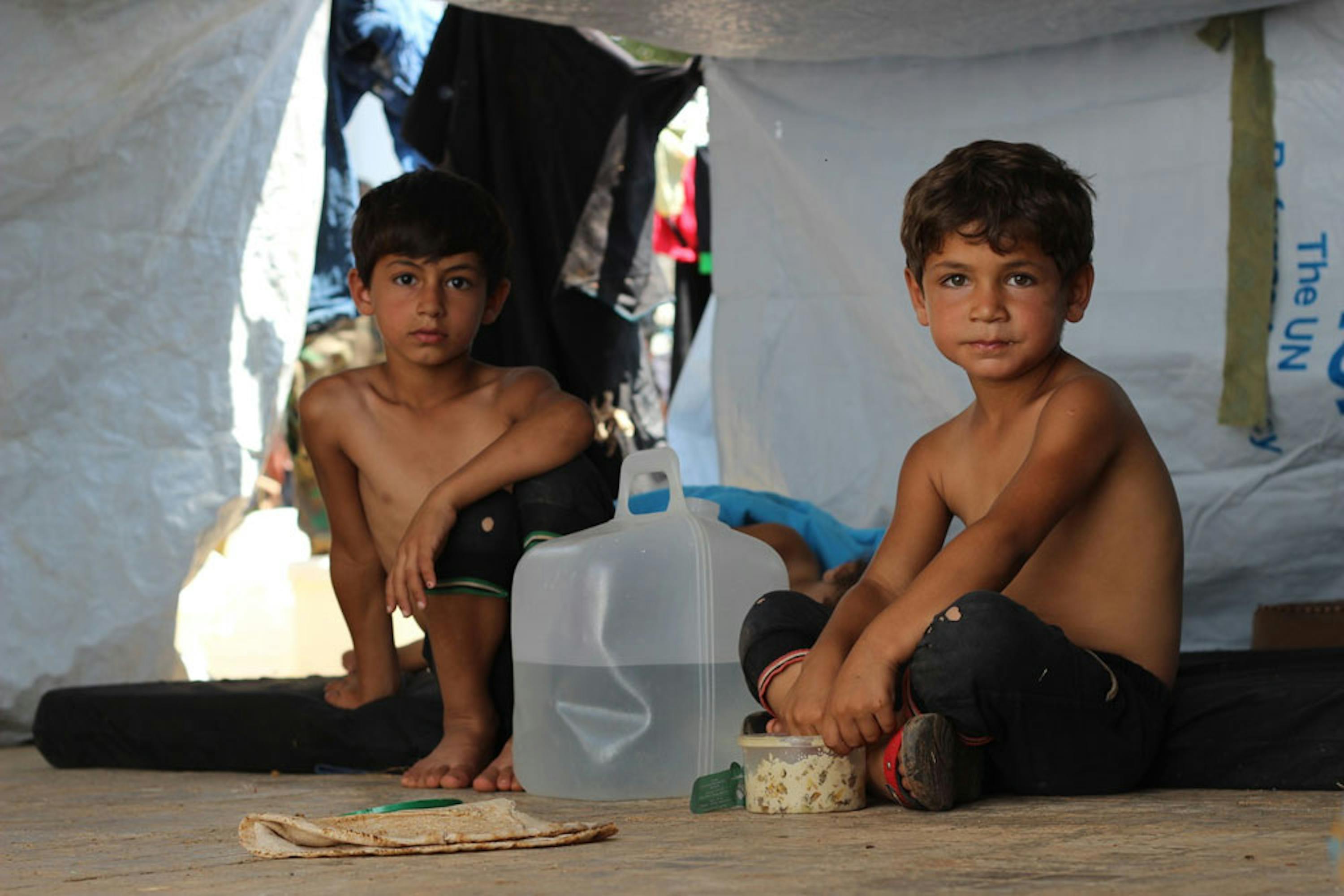 Due fratellini in un accampamento allestito accanto a un'autostrada, nella parte ovest di Aleppo (Siria) per accogliere migliaia di sfollati dalla zona est della città - ©UNICEF/UN027713/Al-Issa