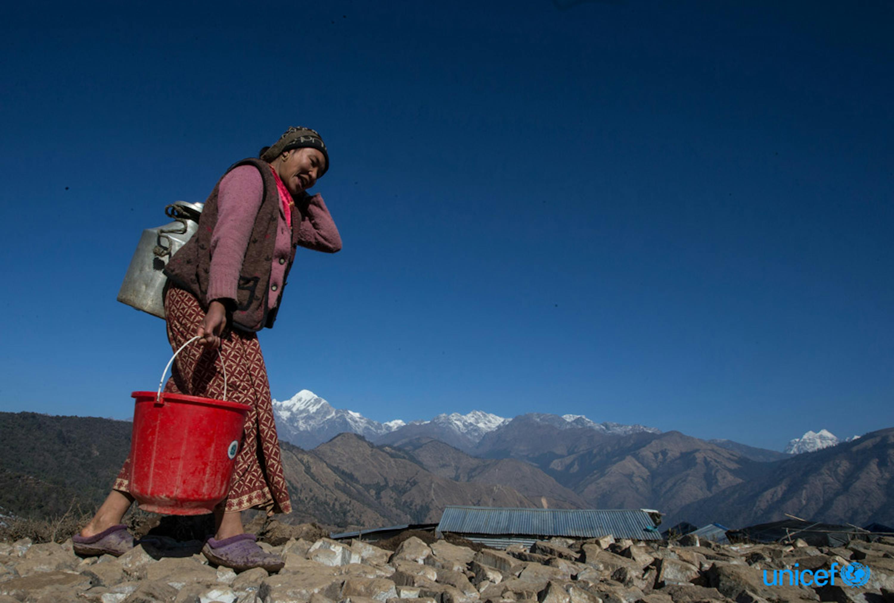 Nepal - Maya Gurung, di 30 anni, trasporta l'acqua nel suo rifugio temporaneo a Gupsi Pakha © UNICEF/UN017117/Shrestha