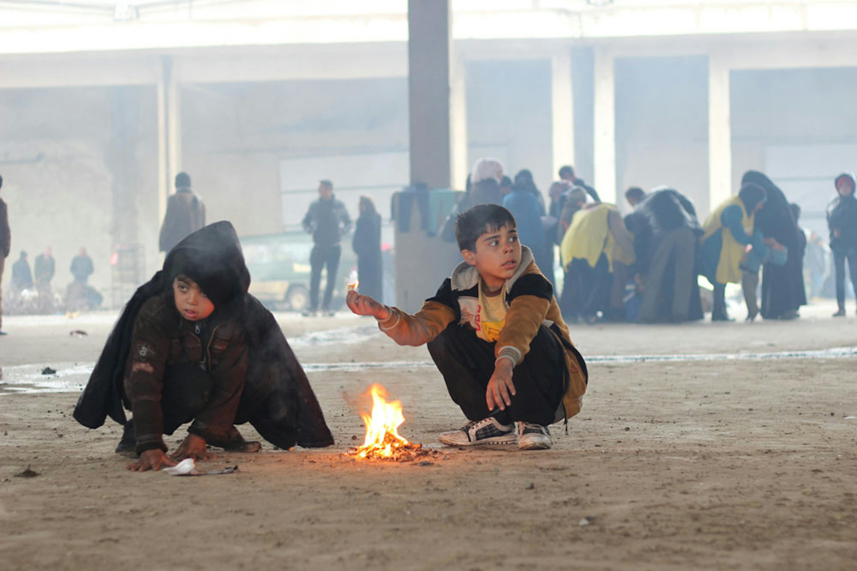 Bambini si scaldano bruciando materiali trovati in giro in questo capannone di Jibreen, sobborgo a est di Aleppo, dove hanno trovato rifugio - ©UNICEF Siria/2016/Al-Issa